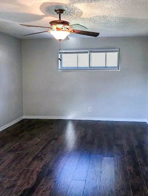 Room featuring wood-finish flooring, a ceiling fan with integrated lighting, and a single window with horizontal panes
