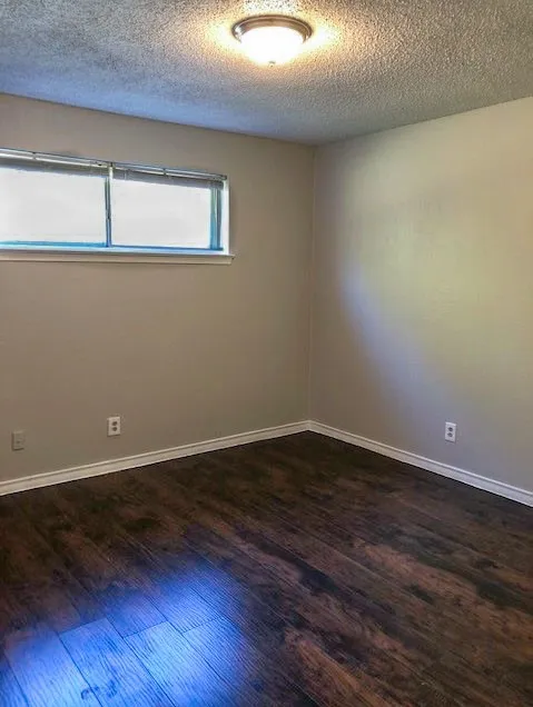 Room featuring wood-finish flooring, a window with blinds, a flush-mount ceiling light, and light-toned wall paint
