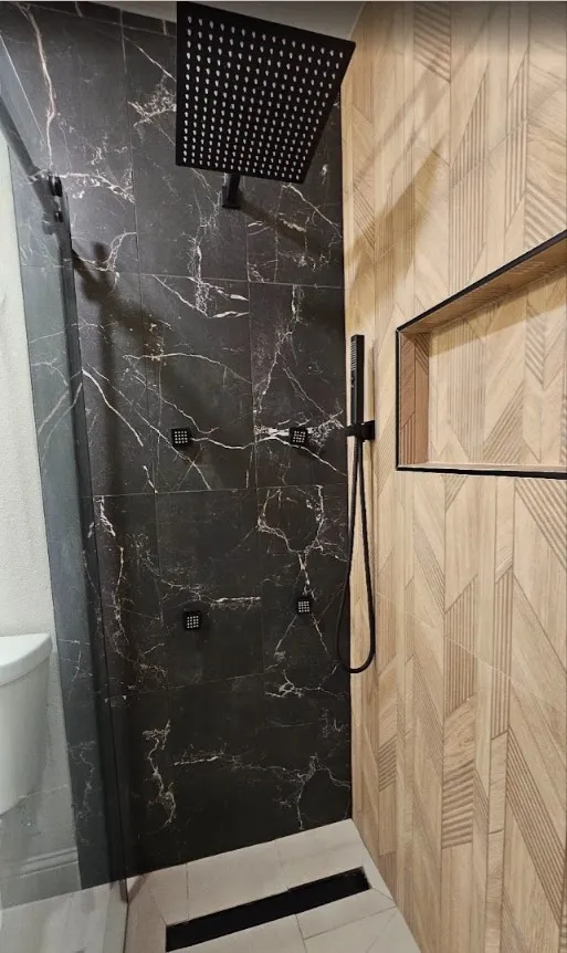 Full bath featuring a marble finish shower and toilet