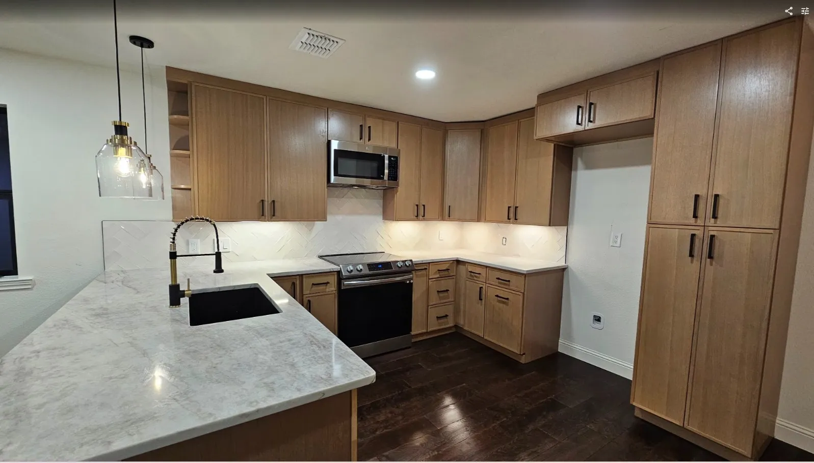 Kitchen featuring open shelves, hanging light fixtures, appliances with stainless steel finishes, light stone counters, and dark wood-style flooring