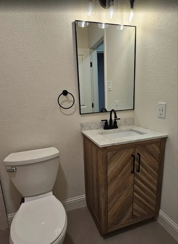 Bathroom with a textured wall, vanity, and dark tile patterned floors