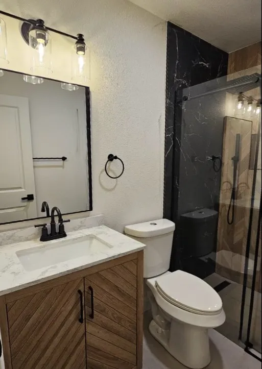 Full bathroom with a textured wall, vanity, and a marble finish shower