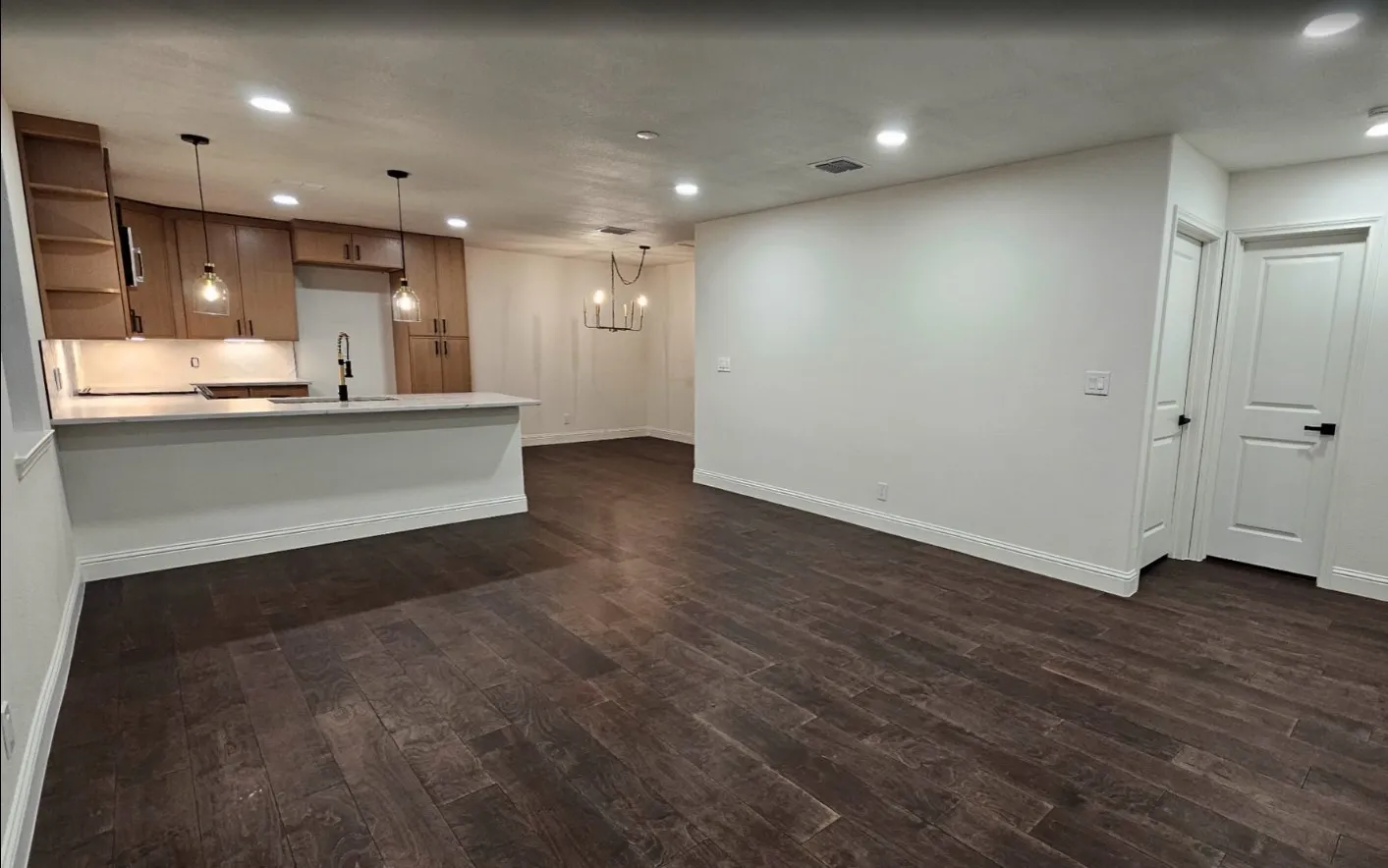 Kitchen featuring recessed lighting, light countertops, pendant lighting, dark wood-style flooring, and a peninsula