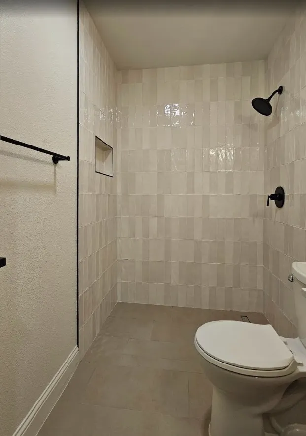 Full bathroom with a tile shower and a textured wall