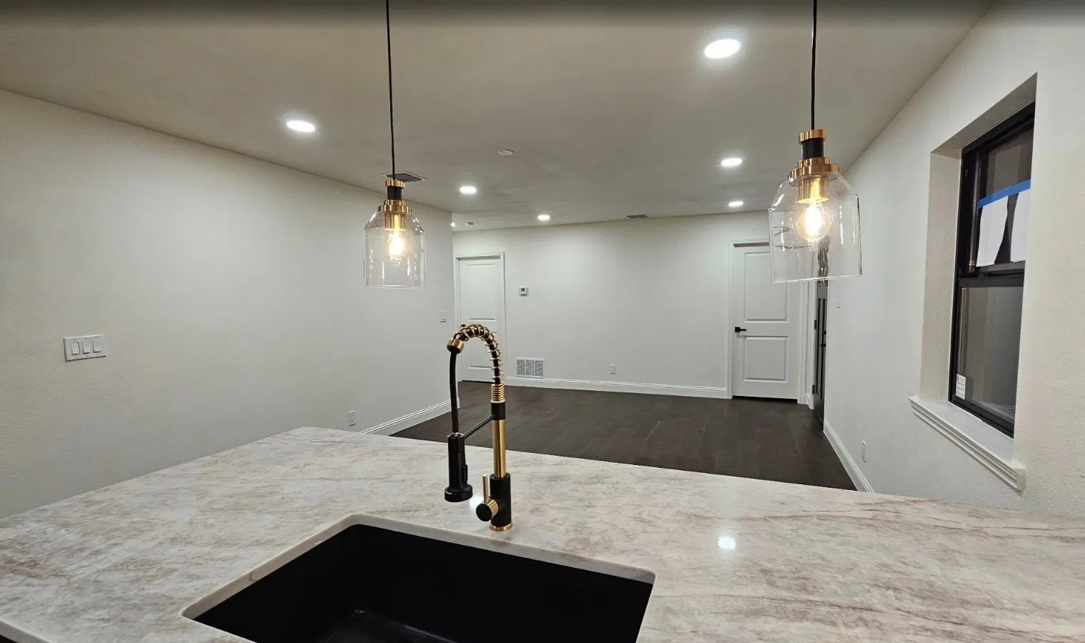 Kitchen featuring decorative light fixtures, recessed lighting, open floor plan, dark wood-type flooring, and light stone countertops