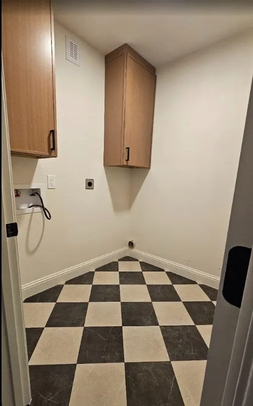 Laundry room featuring cabinet space, dark flooring, and hookup for an electric dryer