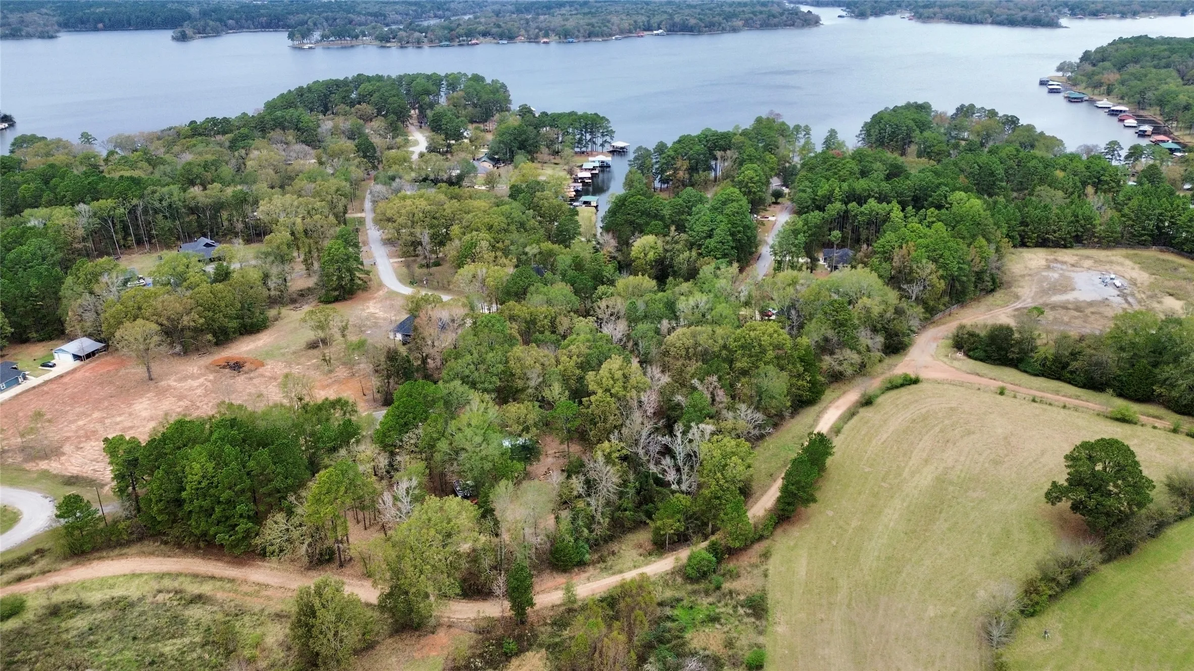 Aerial view of property and surrounding area featuring a forest and a large body of water