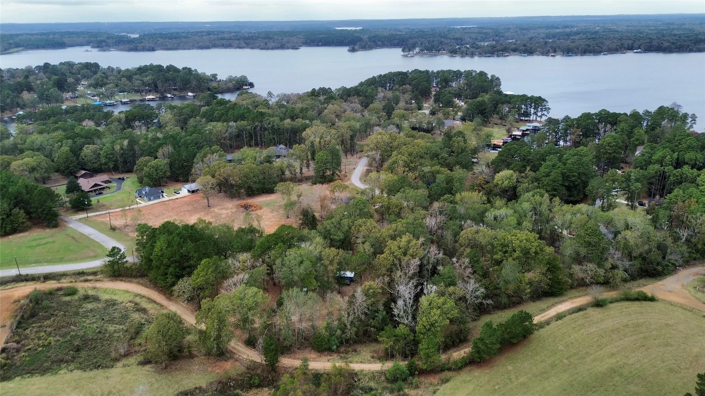 Aerial view of property and surrounding area with a heavily wooded area and a nearby body of water