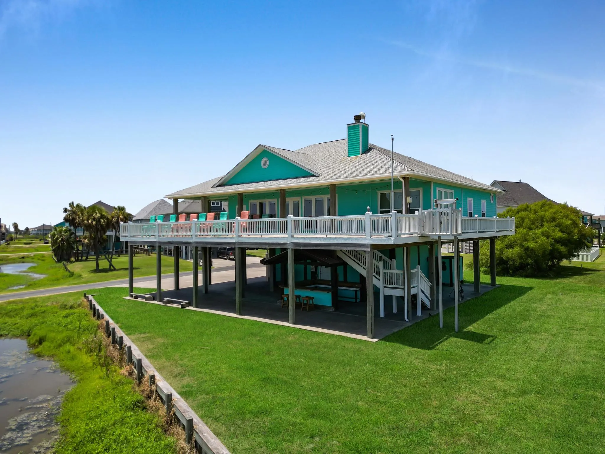 Elevated structure with a spacious deck, exterior staircase, ground-level covered patio, and large windows