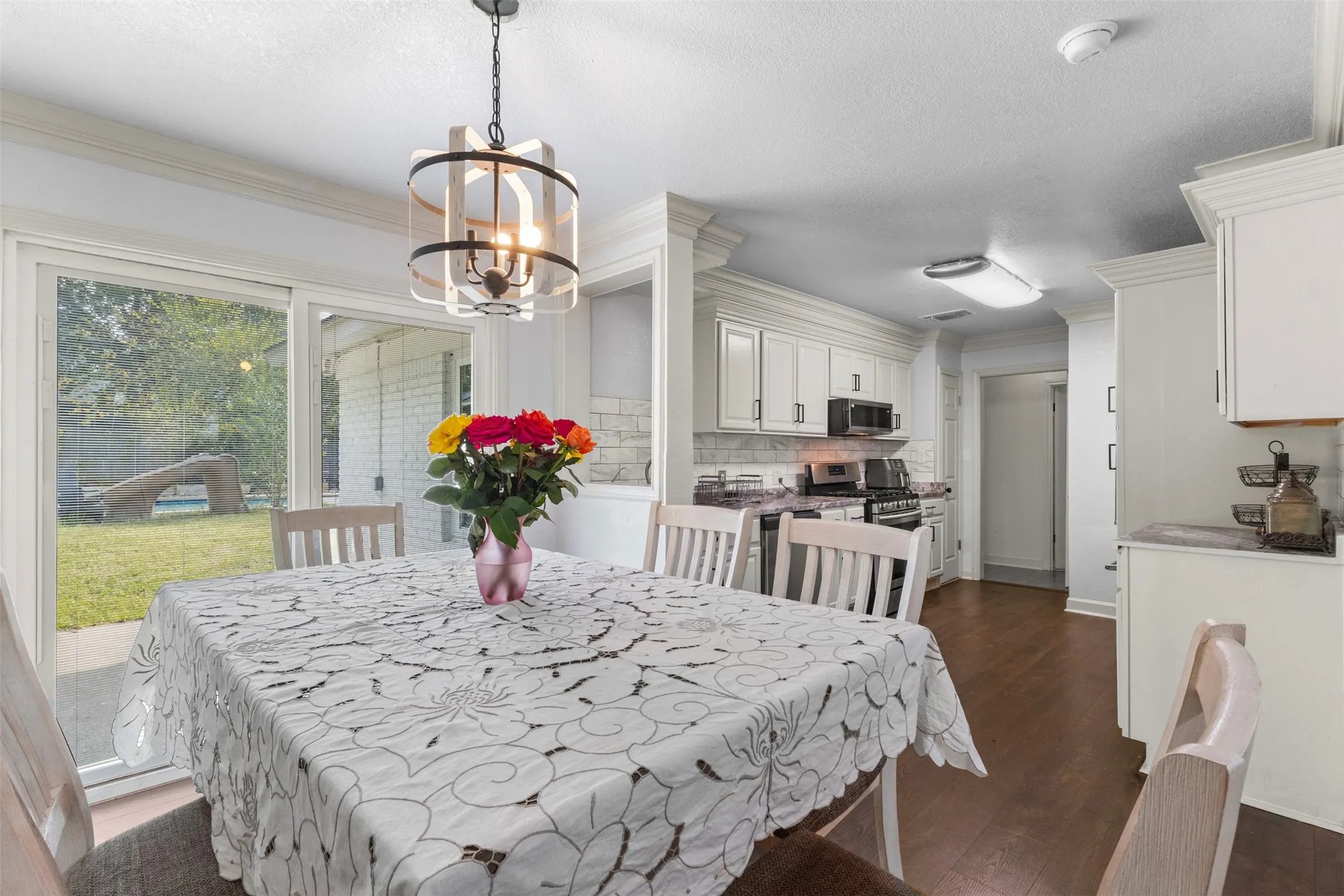 Dining room with crown molding, dark wood finished floors, a chandelier, and a textured ceiling