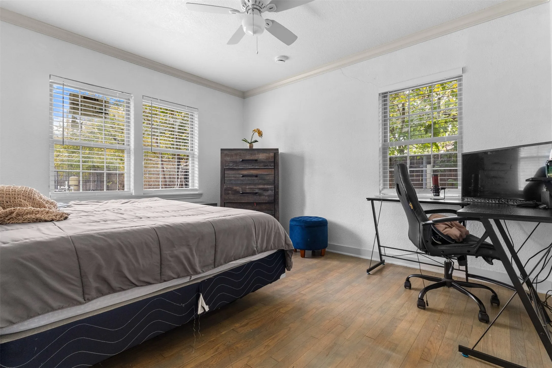 Bedroom featuring an office area, ornamental molding, wood-type flooring, and ceiling fan