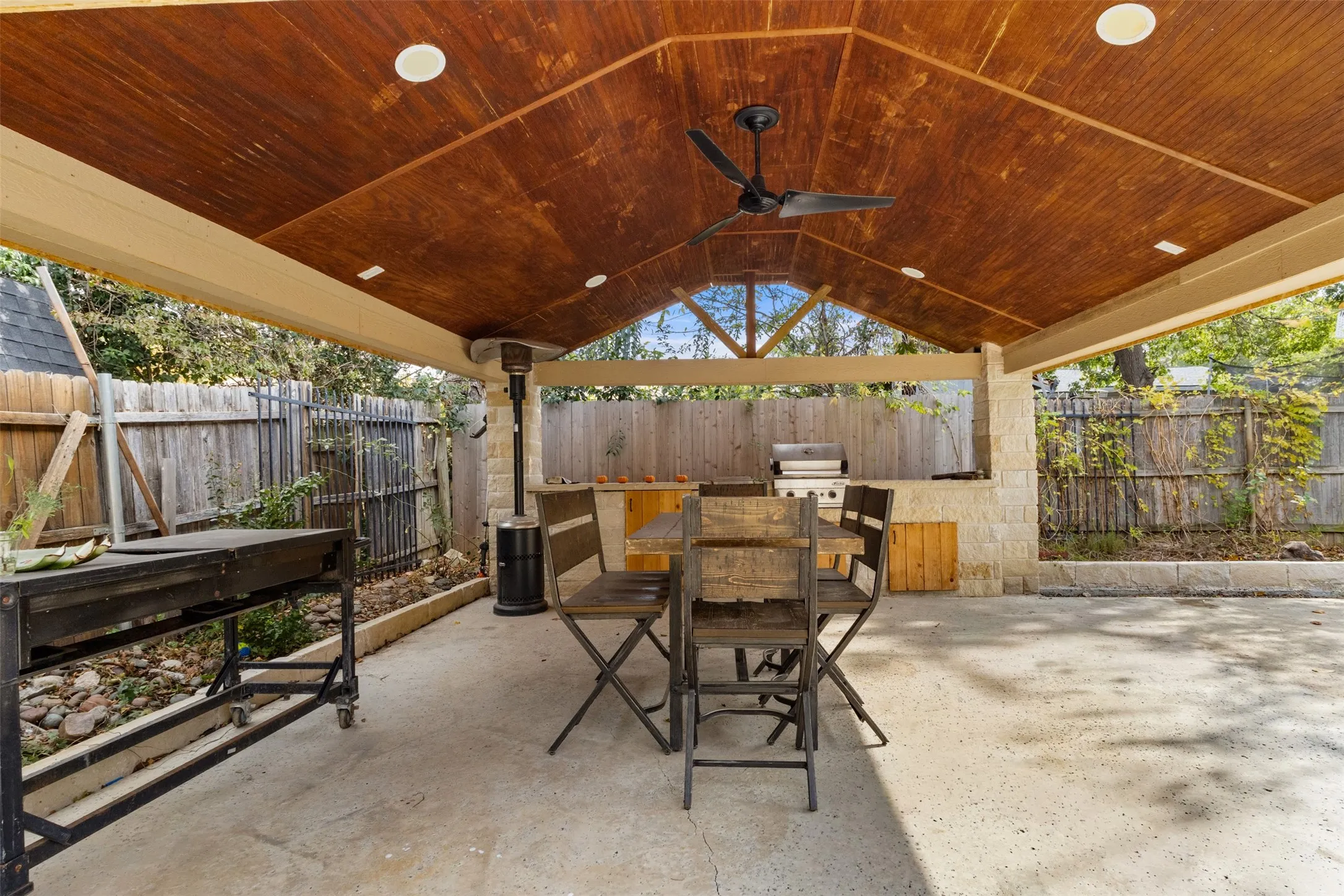 Fenced backyard featuring ceiling fan, a patio area, outdoor dining space, and area for grilling