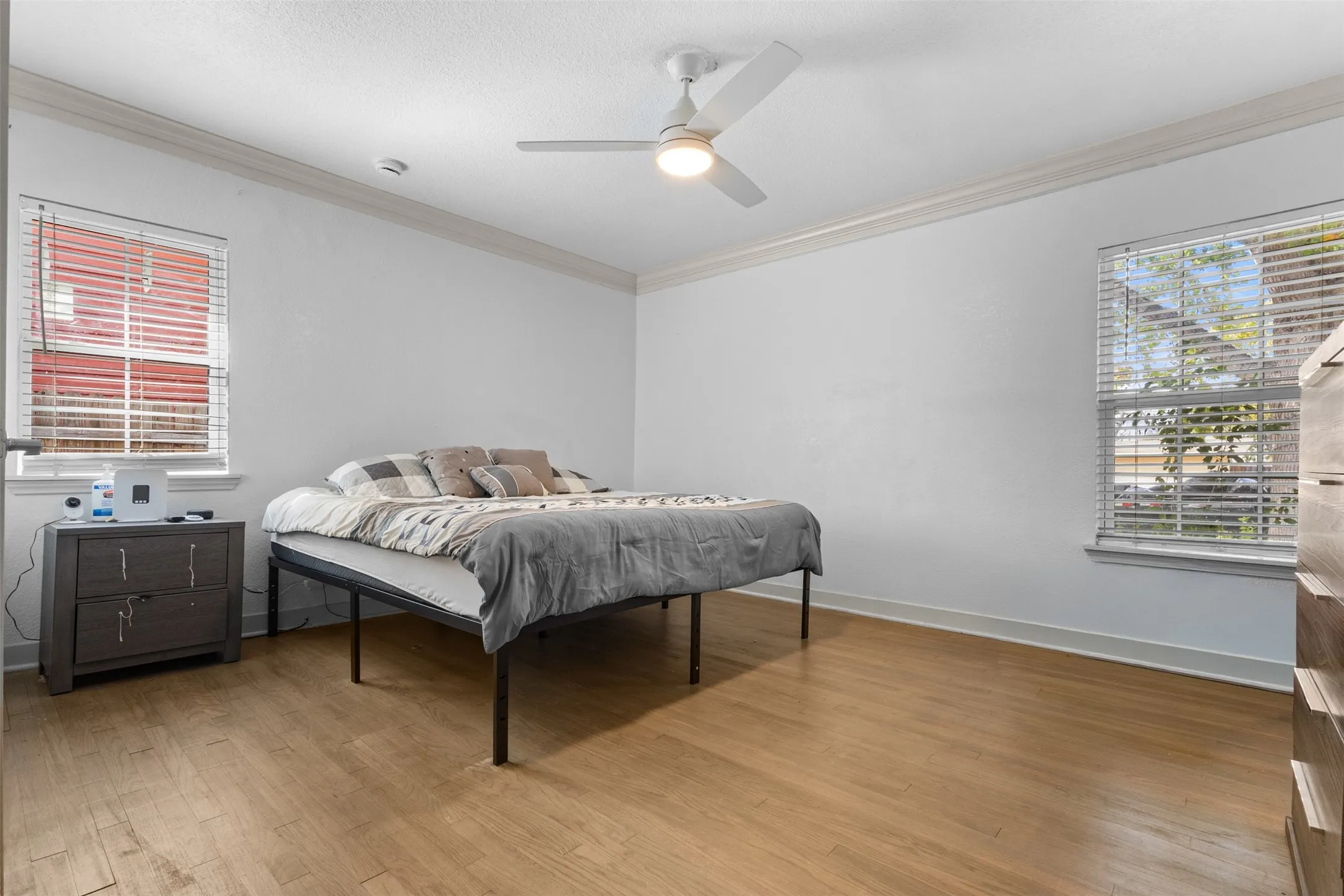 Bedroom with light wood-style flooring, ceiling fan, and ornamental molding
