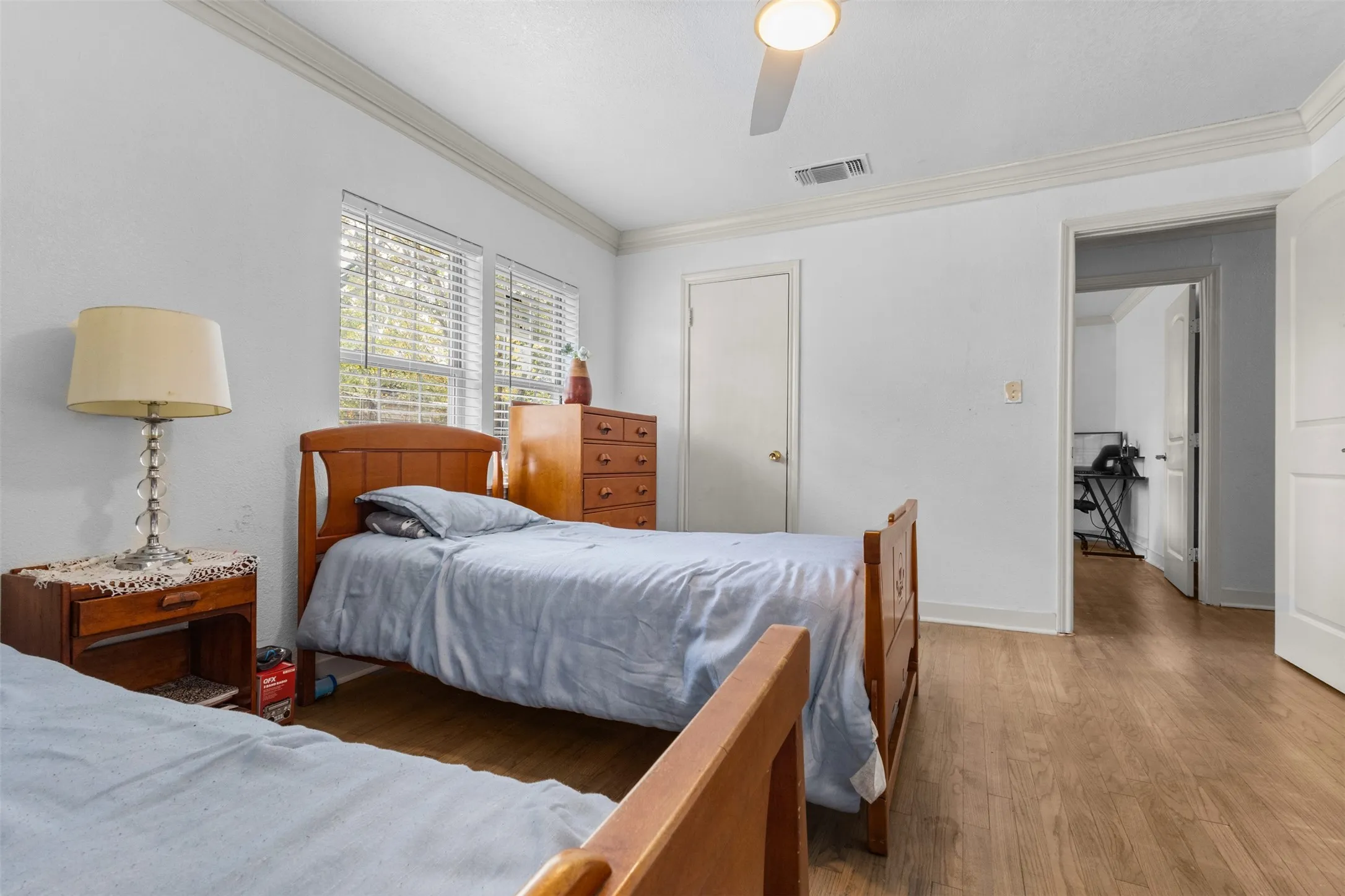 Bedroom with wood finished floors, a closet, crown molding, and a ceiling fan