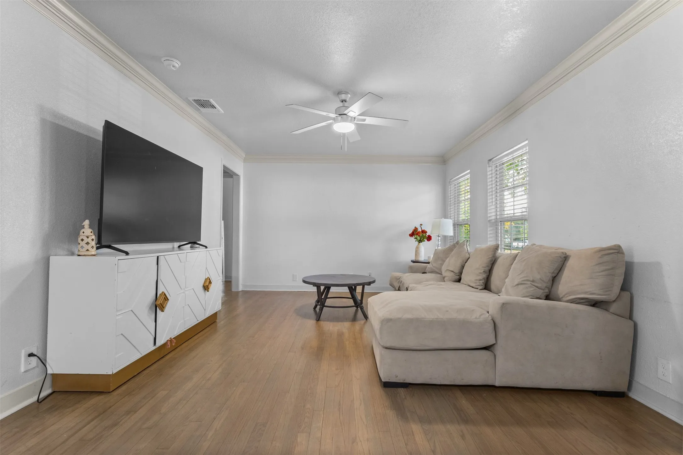 Living room featuring crown molding, a ceiling fan, and wood finished floors