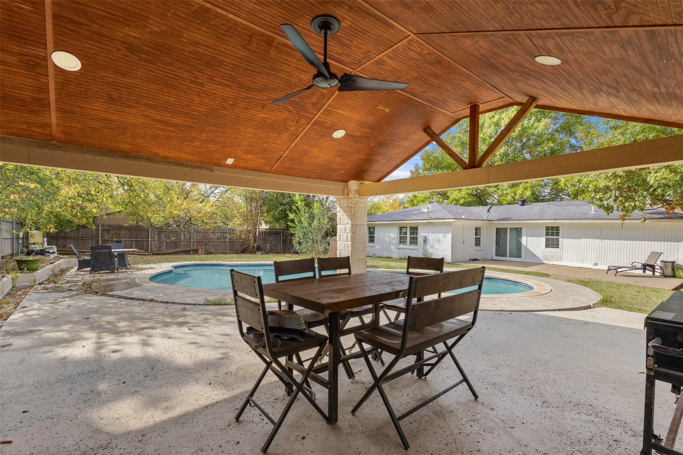 Fenced backyard with a patio, a grill, ceiling fan, and outdoor dining space