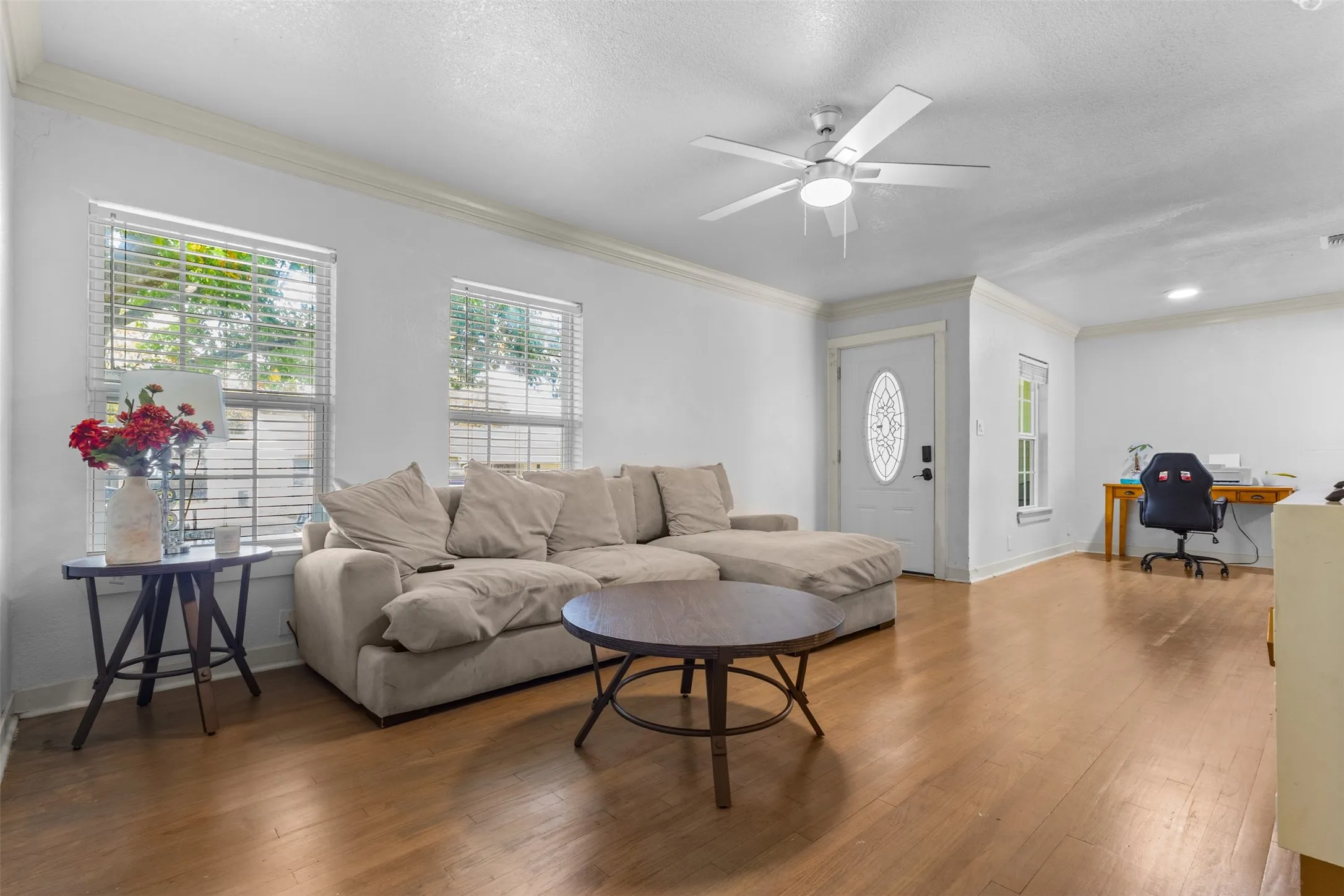 Living area featuring an office area, plenty of natural light, crown molding, wood-type flooring, and a textured ceiling