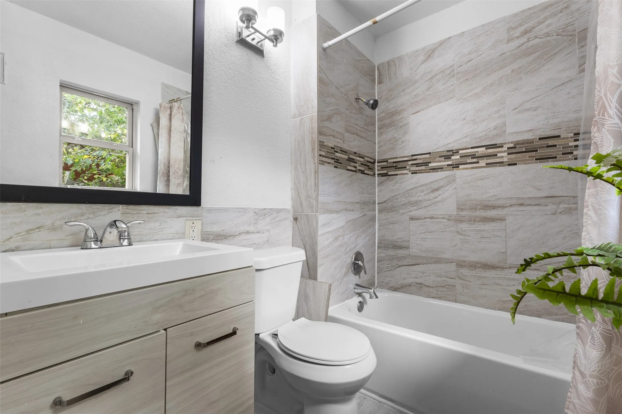 Bathroom with shower / bath combo with shower curtain, vanity, tile walls, and tasteful backsplash