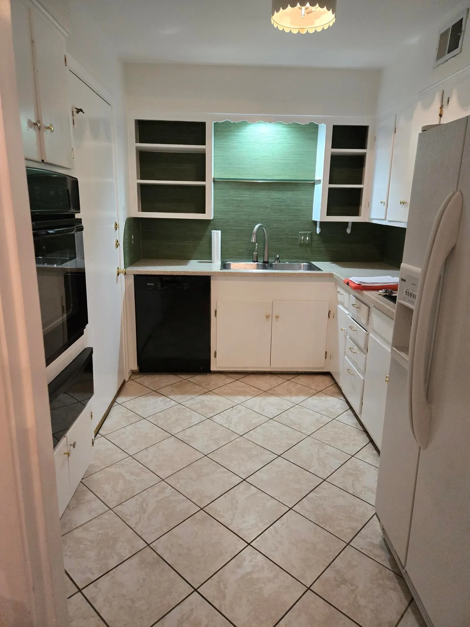Kitchen featuring white cabinetry, built-in double ovens, stainless steel sink, and tile flooring