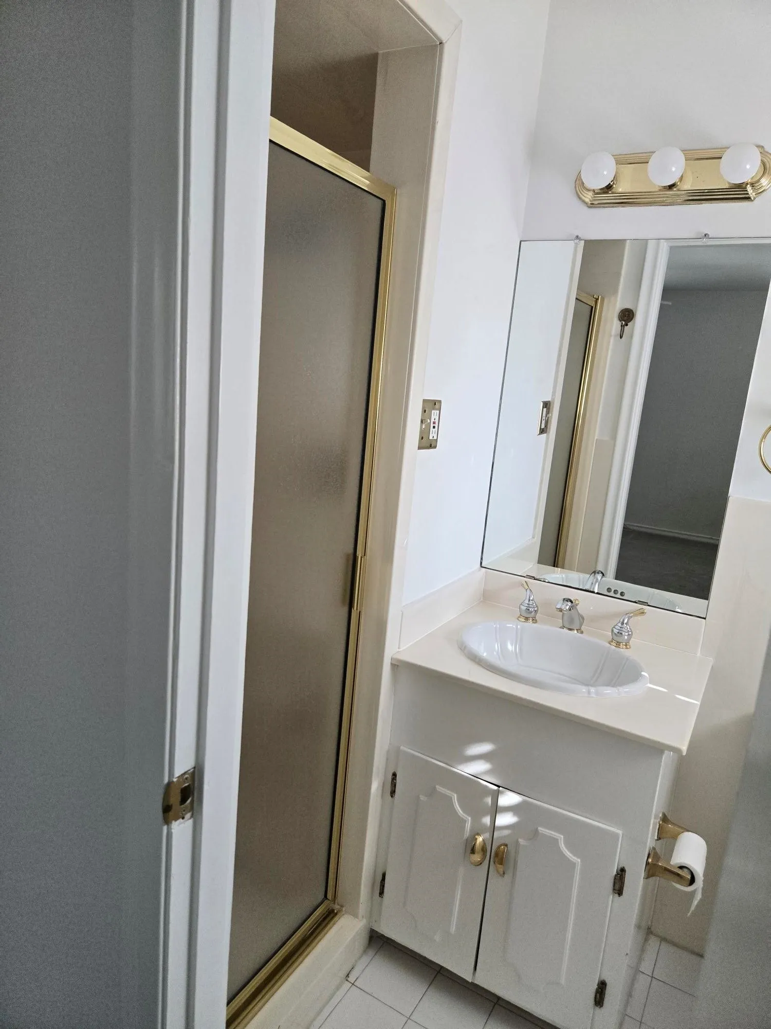 Vanity with an integrated oval sink, brass-finish hardware, and a framed mirror