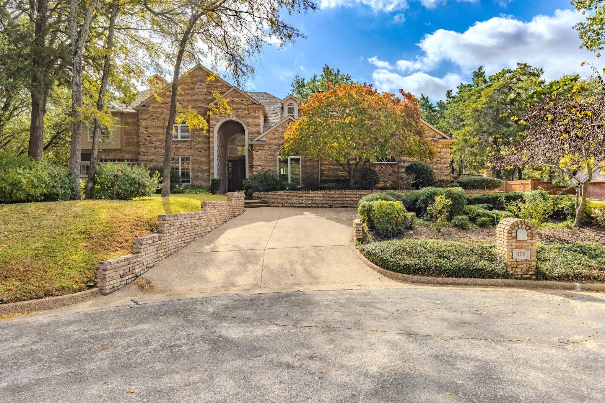 View of front of house with brick siding, driveway, and a front lawn
