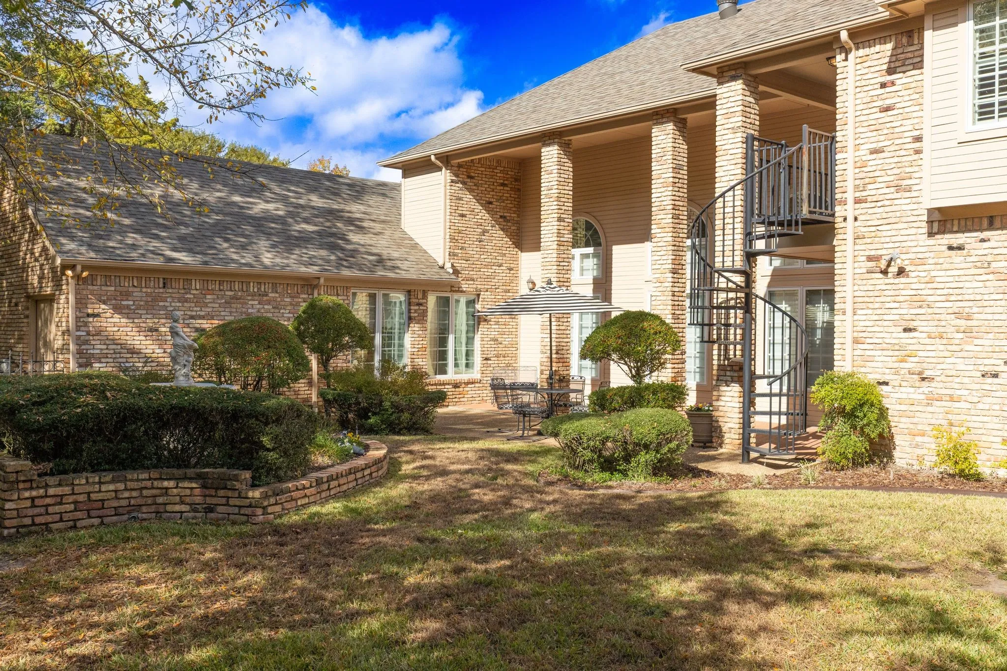 View featuring roof with shingles, stairs, a patio area, brick siding, and a balcony