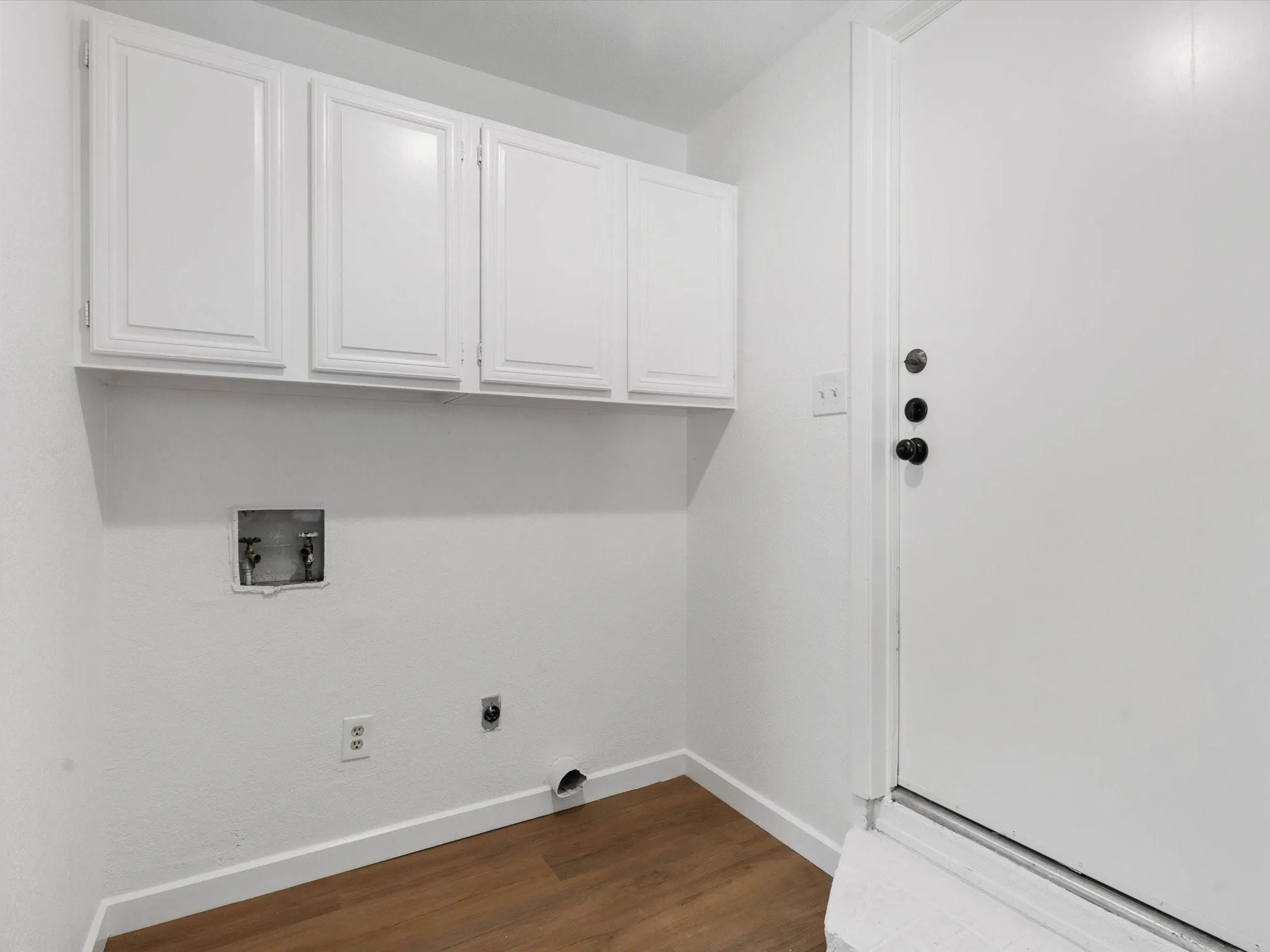 Washroom featuring dark wood finished floors, cabinet space, washer hookup, and hookup for an electric dryer