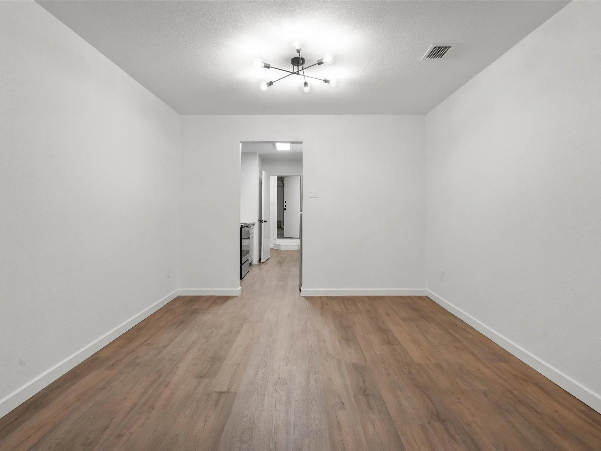 Unfurnished room with wood finished floors and a chandelier