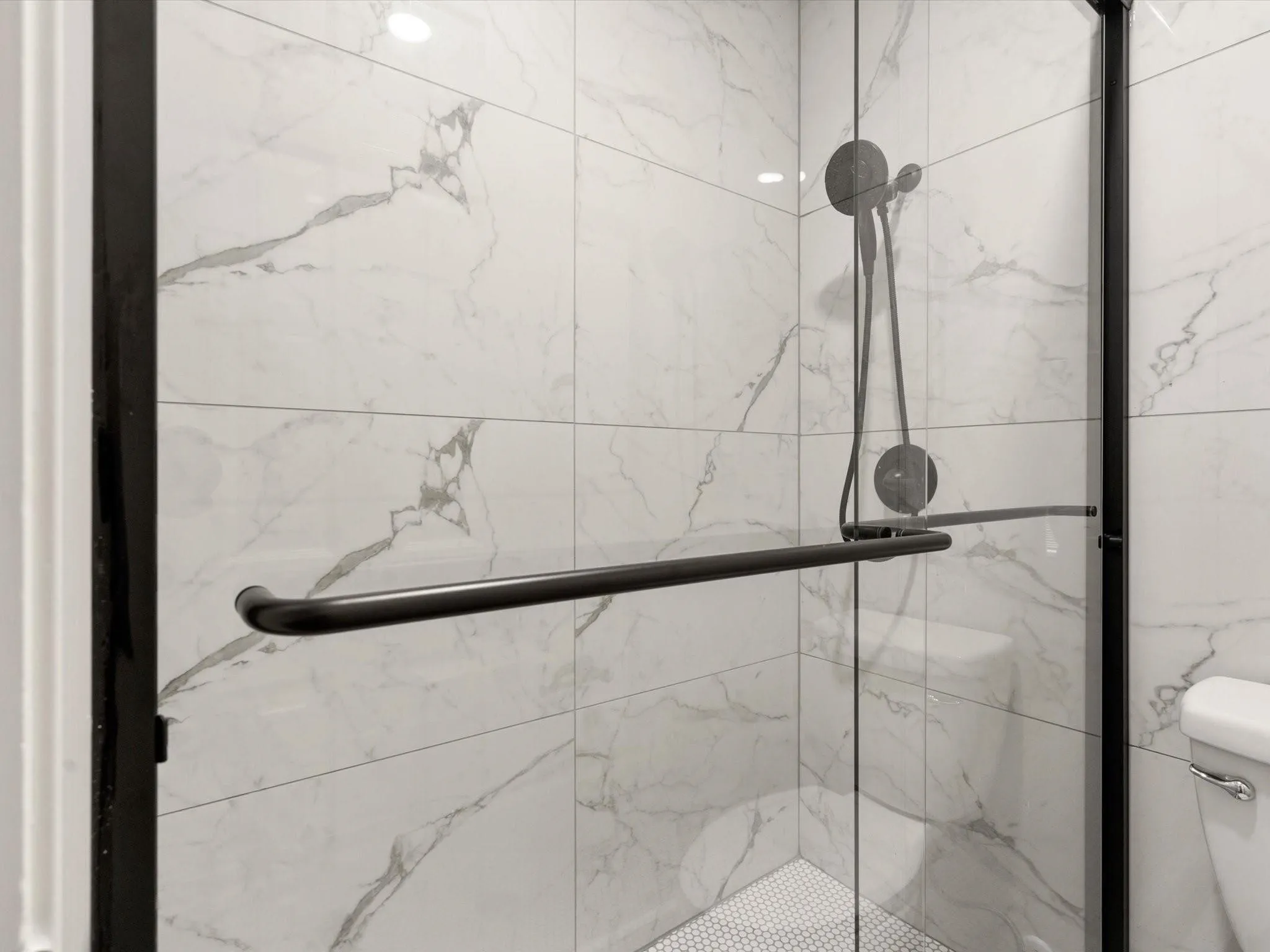 Bathroom view of a marble finish shower and toilet