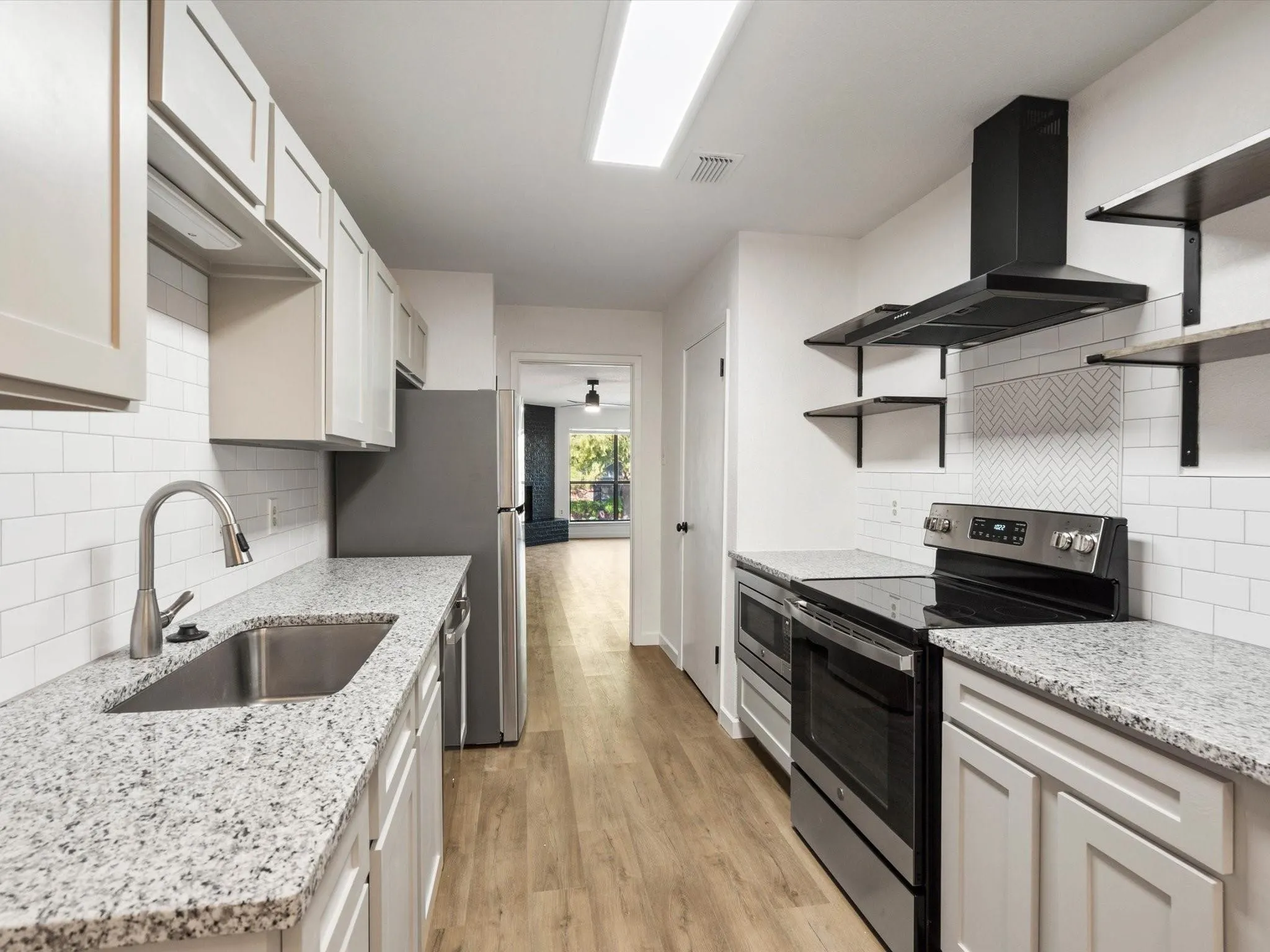 Kitchen featuring open shelves, appliances with stainless steel finishes, ventilation hood, light stone countertops, and tasteful backsplash