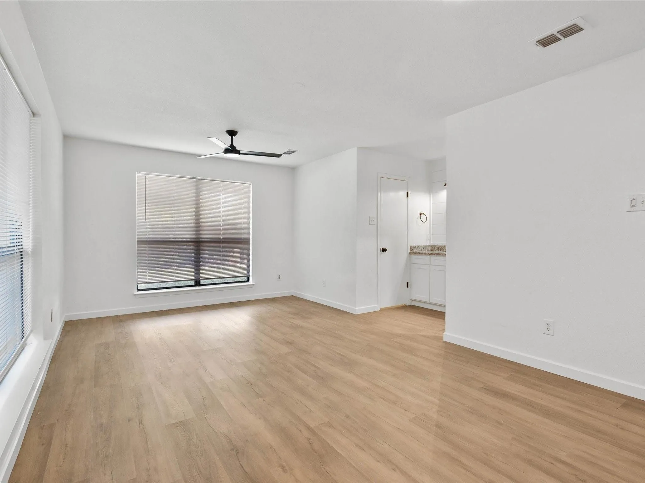 Empty room with light wood finished floors and a ceiling fan