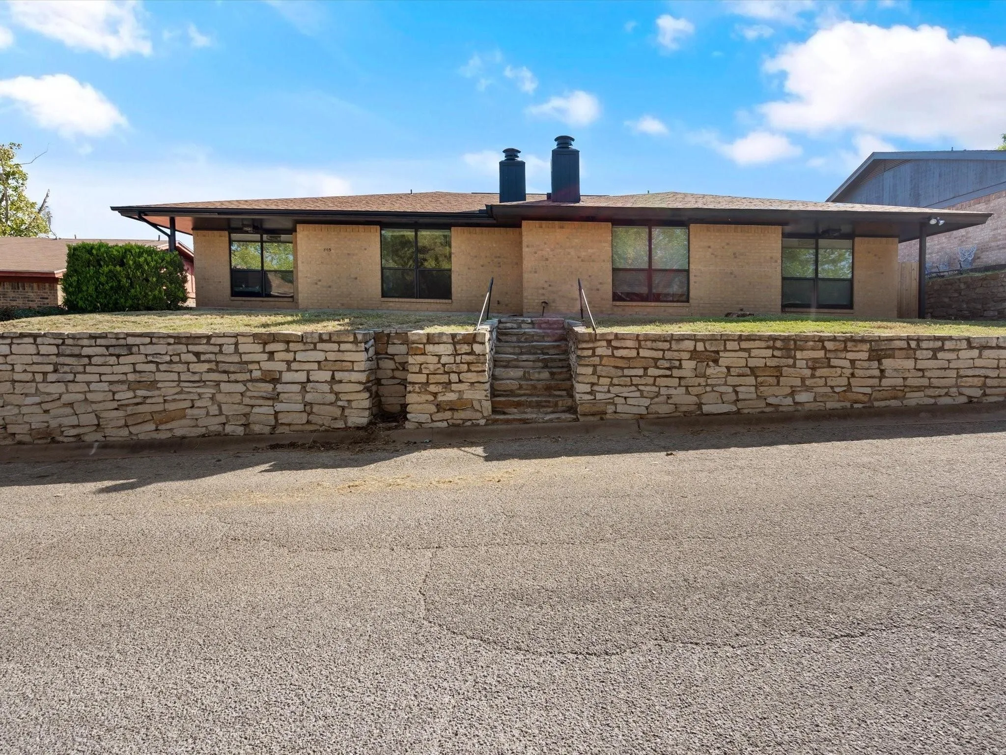 View of front of house with brick siding, a chimney, and roof with shingles