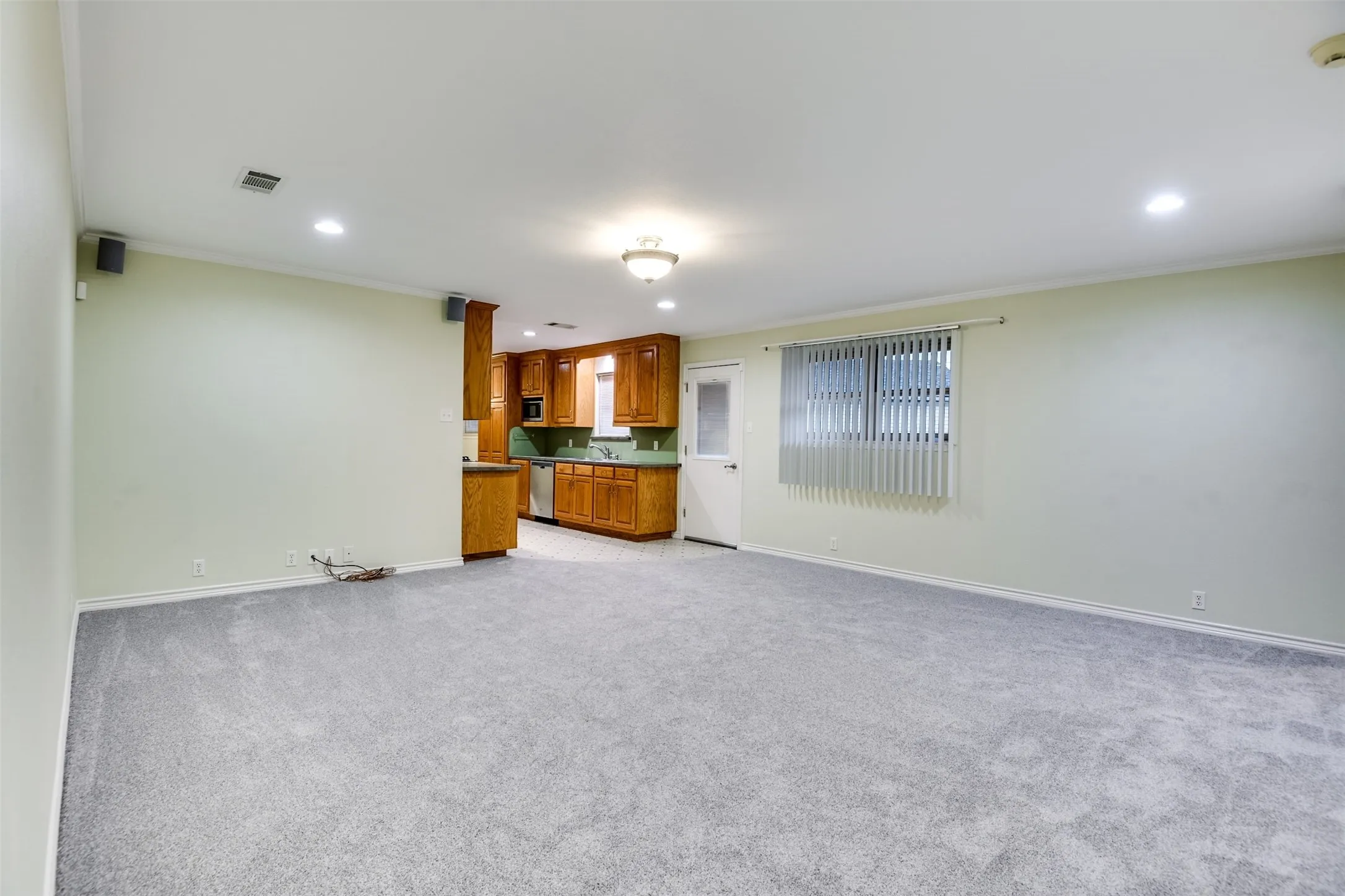 Unfurnished living room with recessed lighting, ornamental molding, and light colored carpet