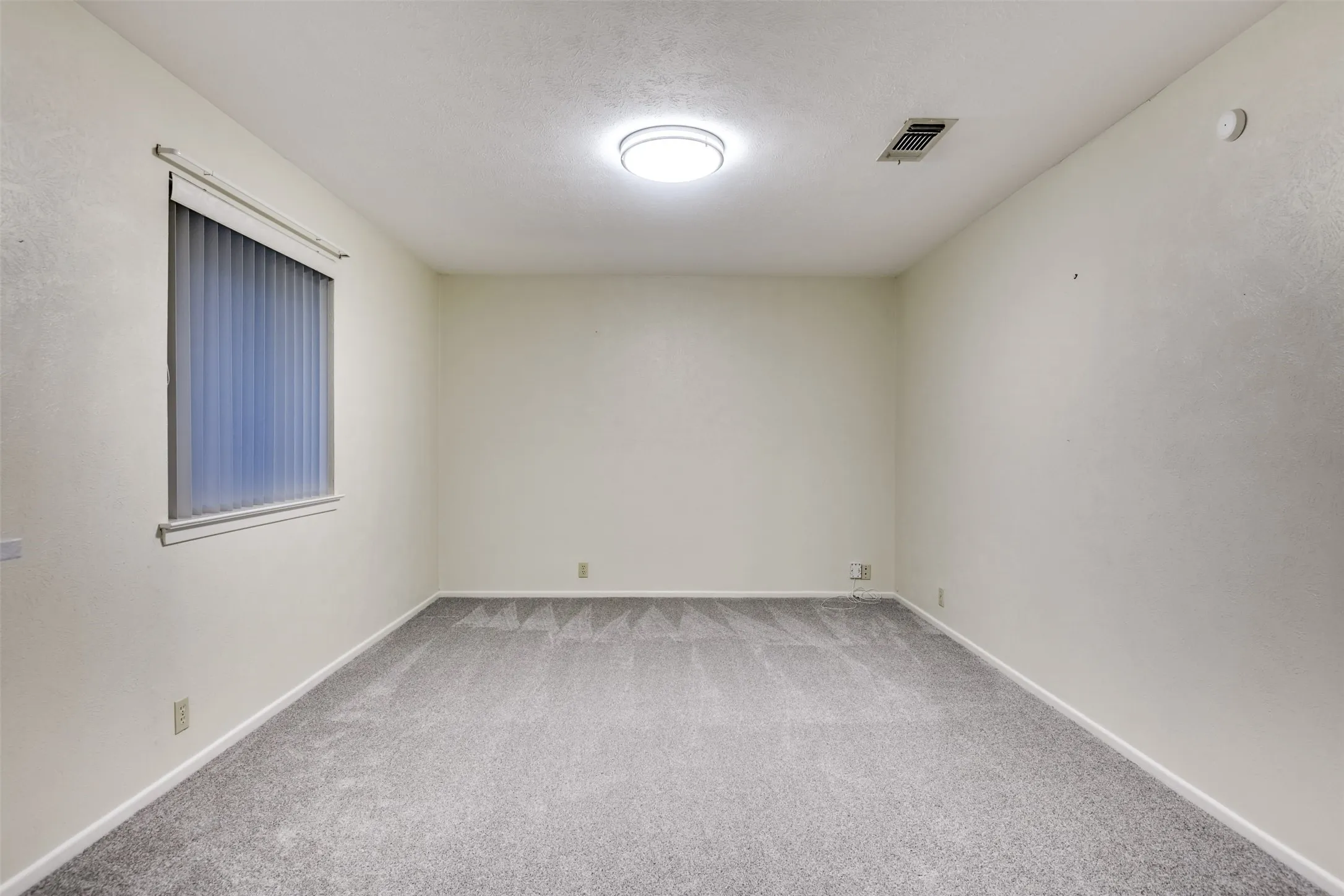 Unfurnished room with light carpet and a textured ceiling