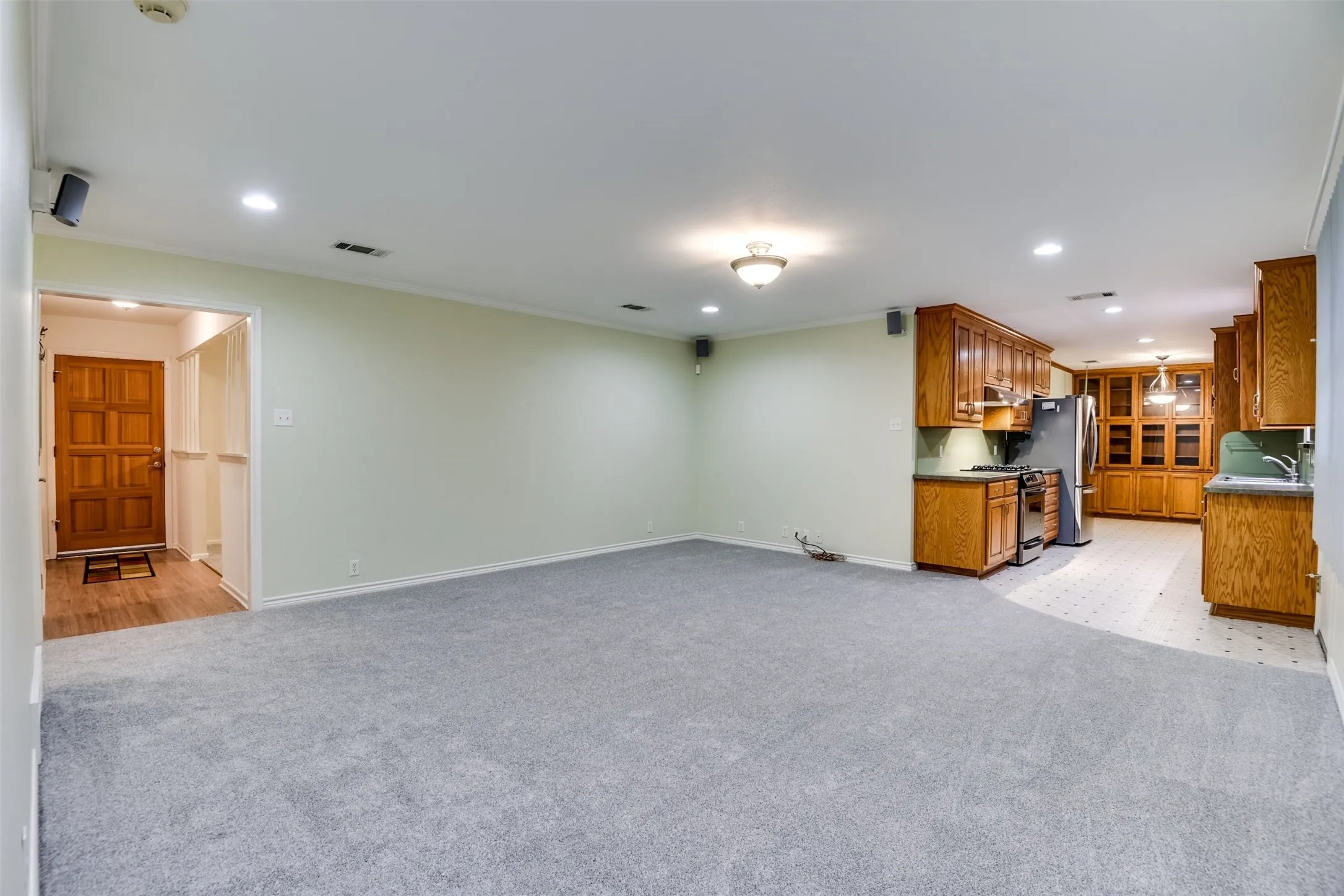 Unfurnished living room featuring recessed lighting, light colored carpet, and ornamental molding