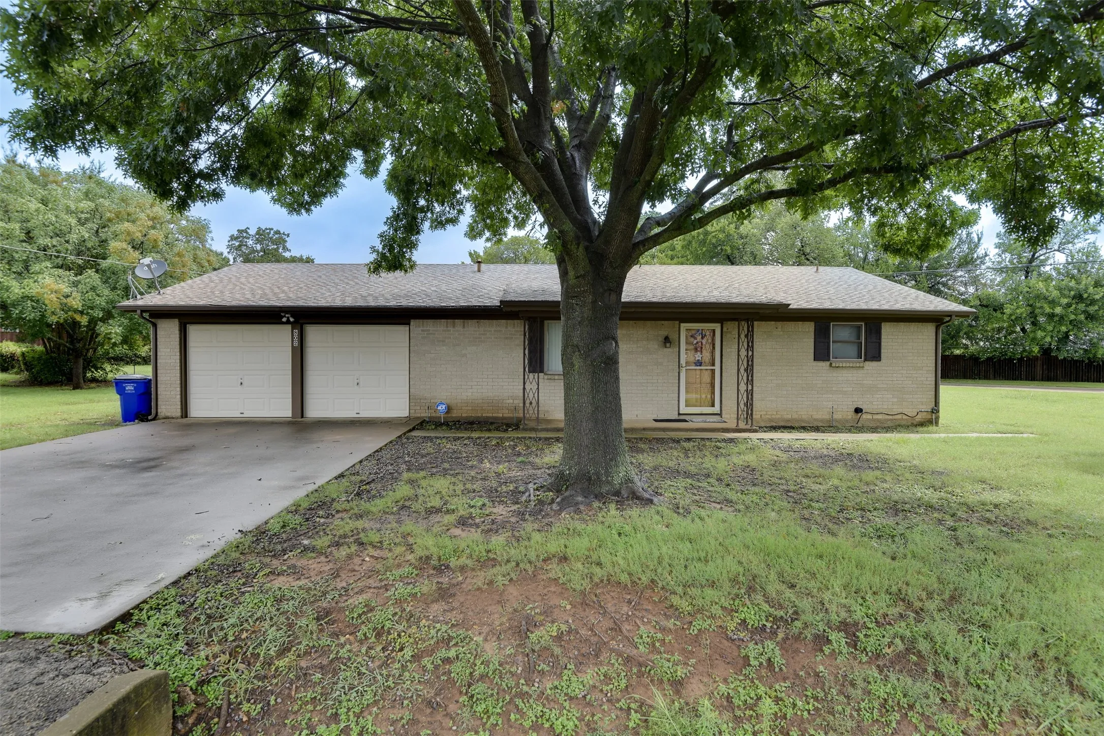 Ranch-style home with driveway, a front yard, a garage, and roof with shingles