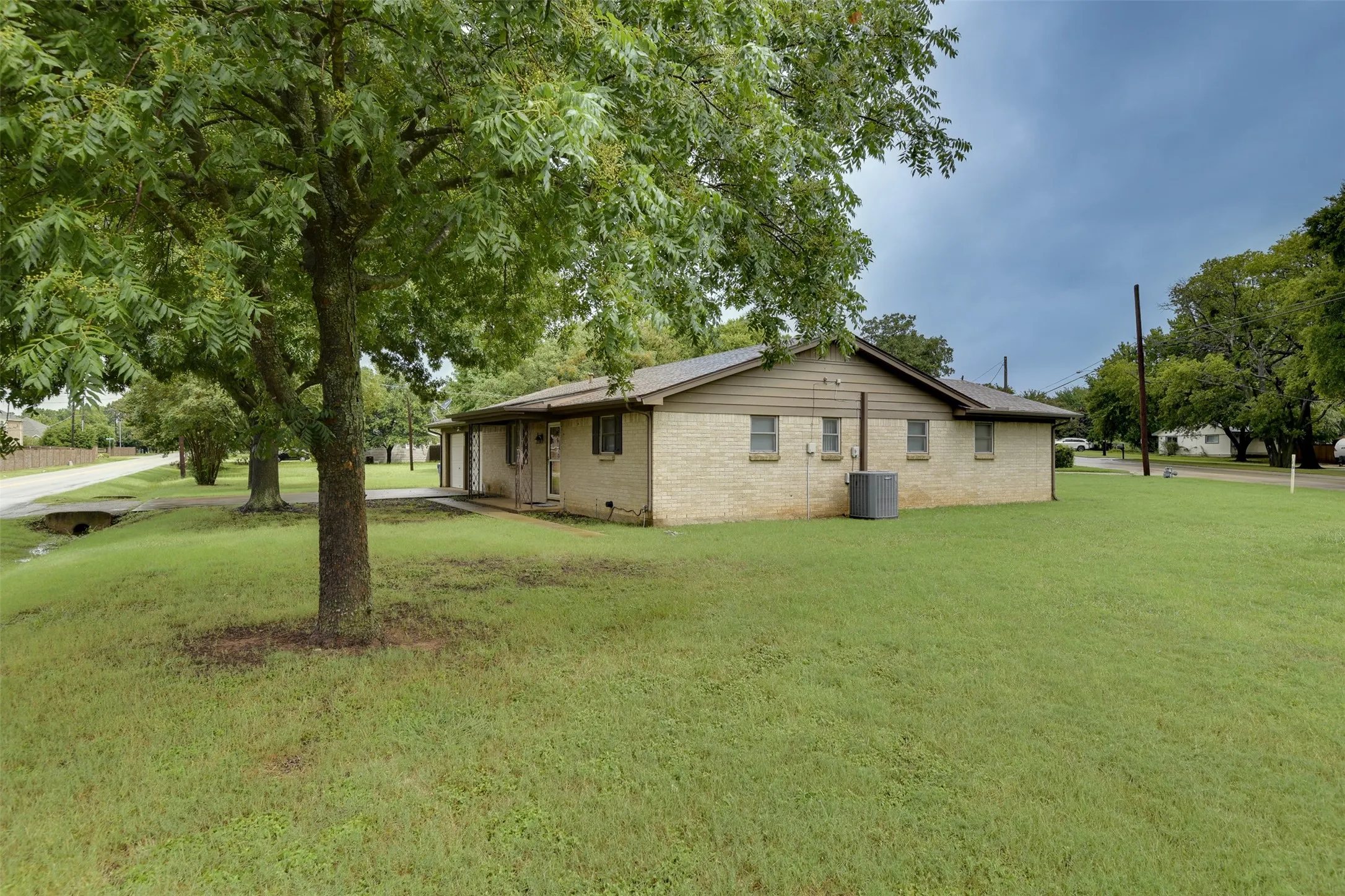 View of property exterior with a lawn and brick siding