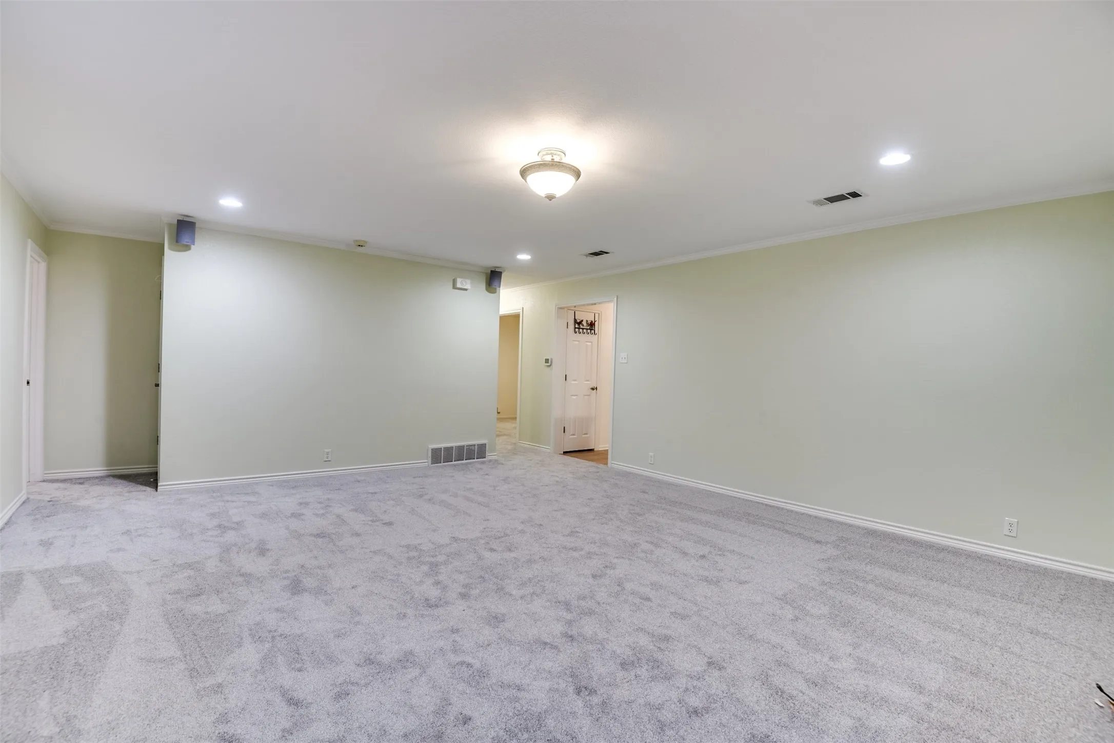 Empty room with recessed lighting, crown molding, and light carpet