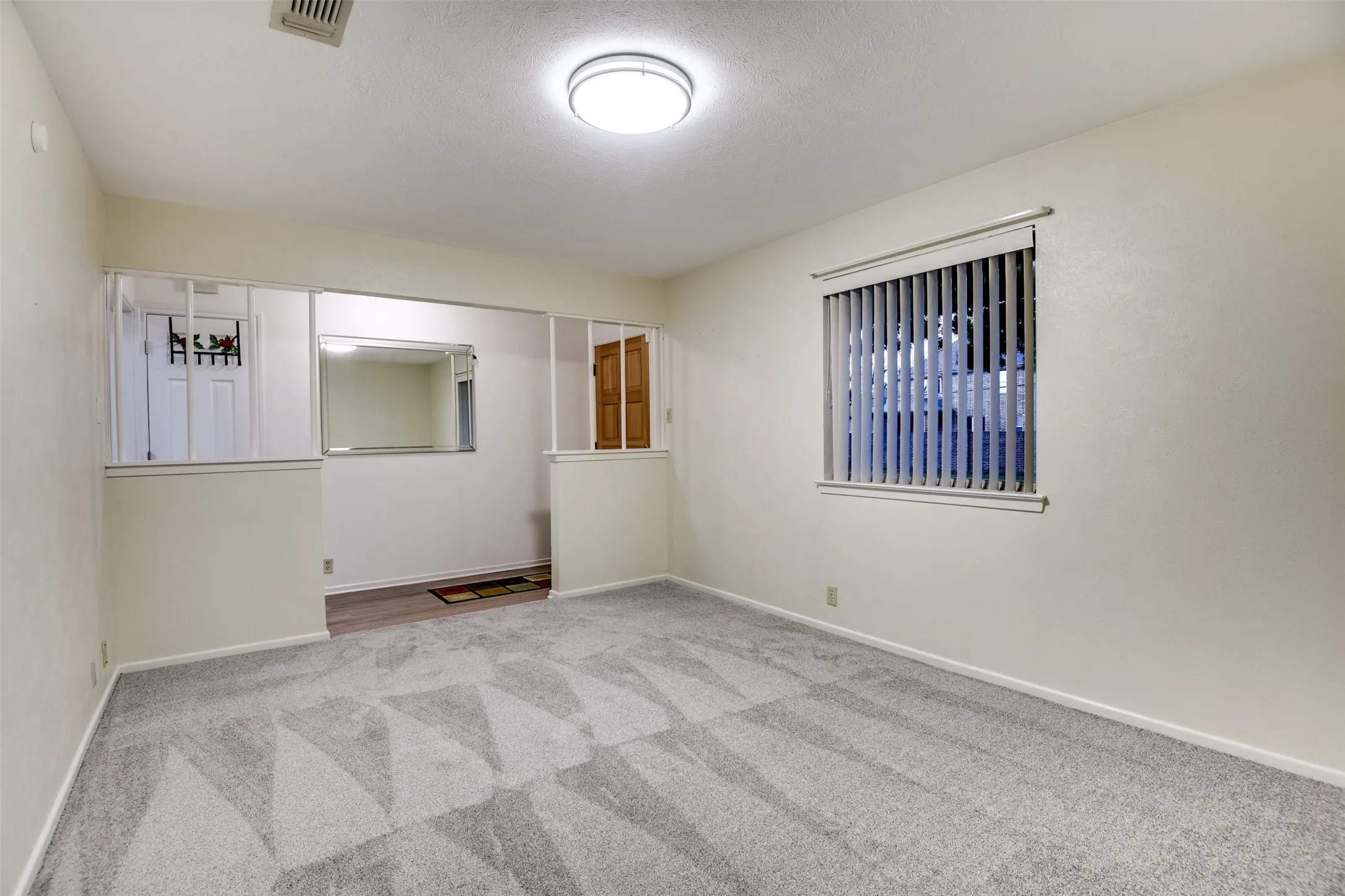 Empty room featuring light colored carpet and a textured ceiling