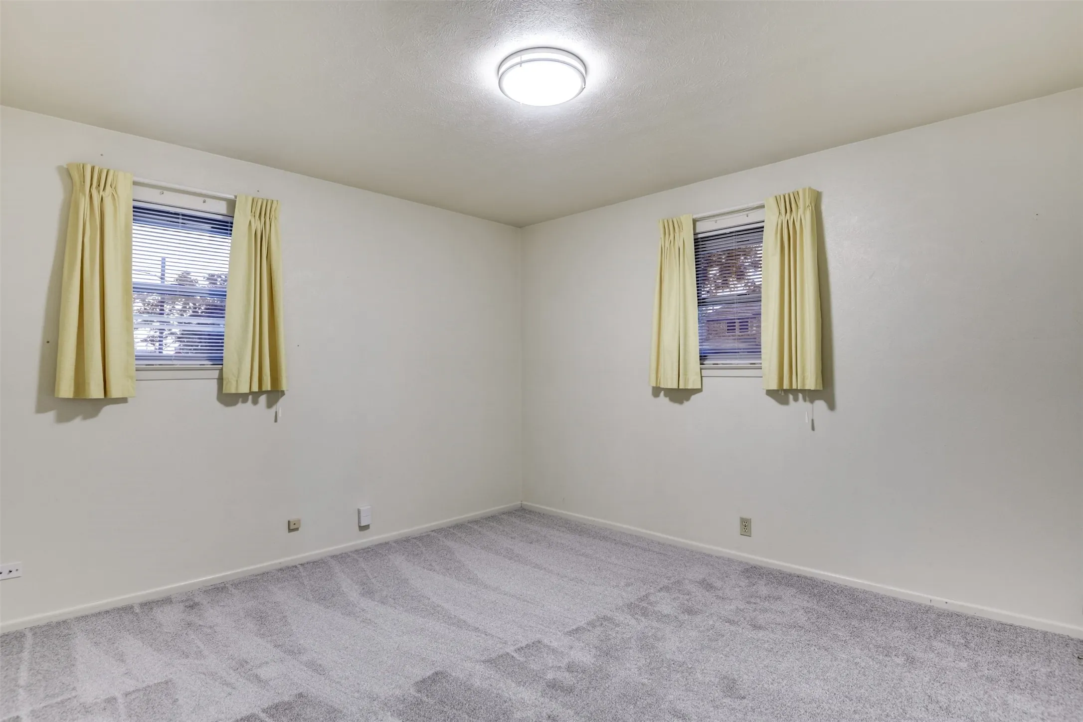 Carpeted spare room featuring baseboards and a textured ceiling