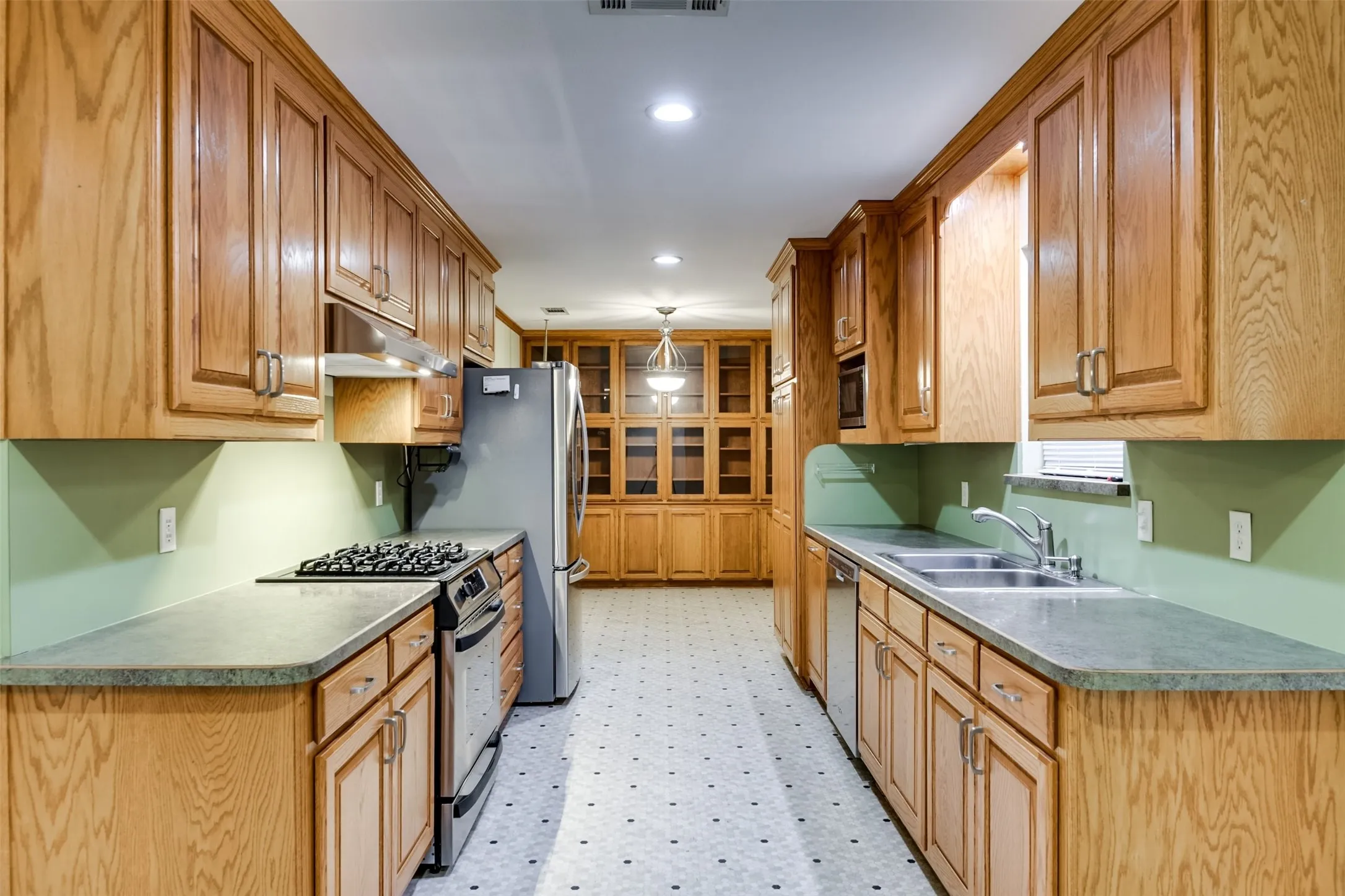 Kitchen featuring light flooring, appliances with stainless steel finishes, under cabinet range hood, pendant lighting, and recessed lighting