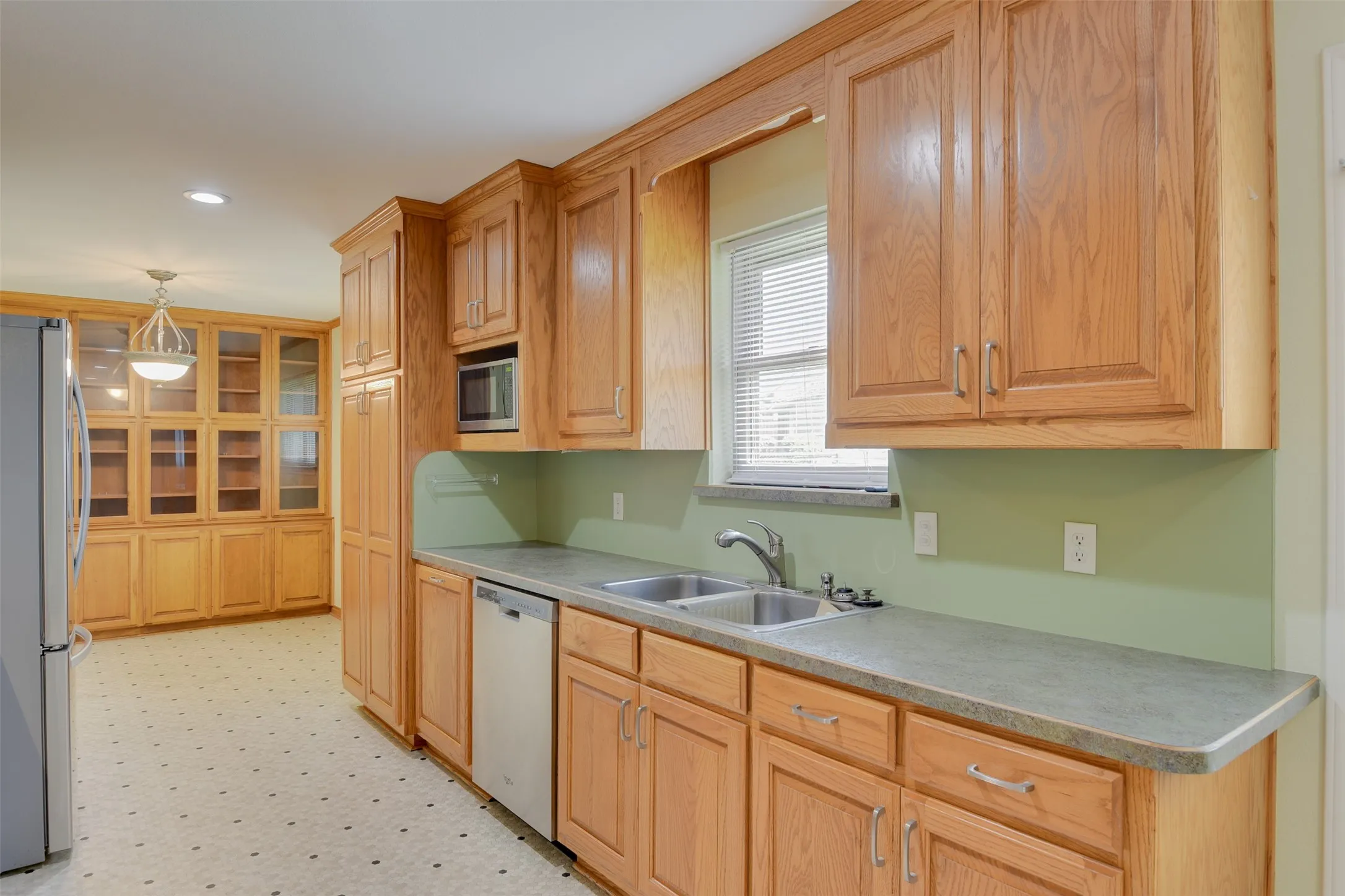 Kitchen featuring stainless steel appliances, light floors, pendant lighting, light countertops, and recessed lighting