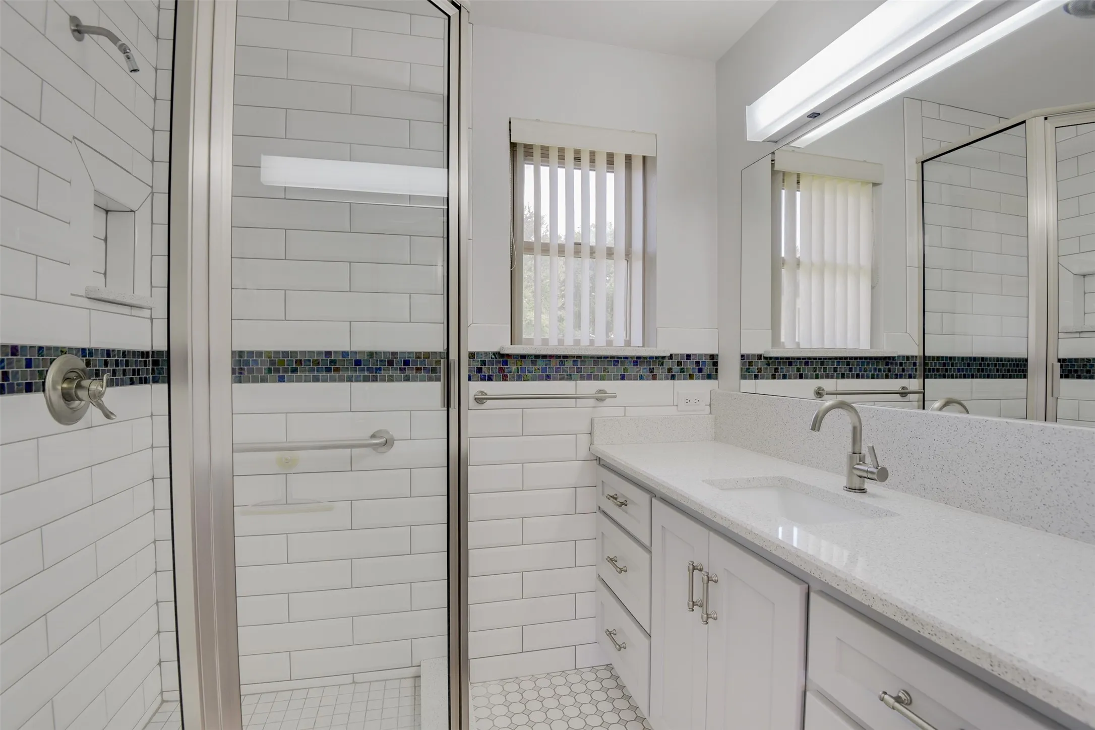 Bathroom with vanity, a stall shower, and tile walls