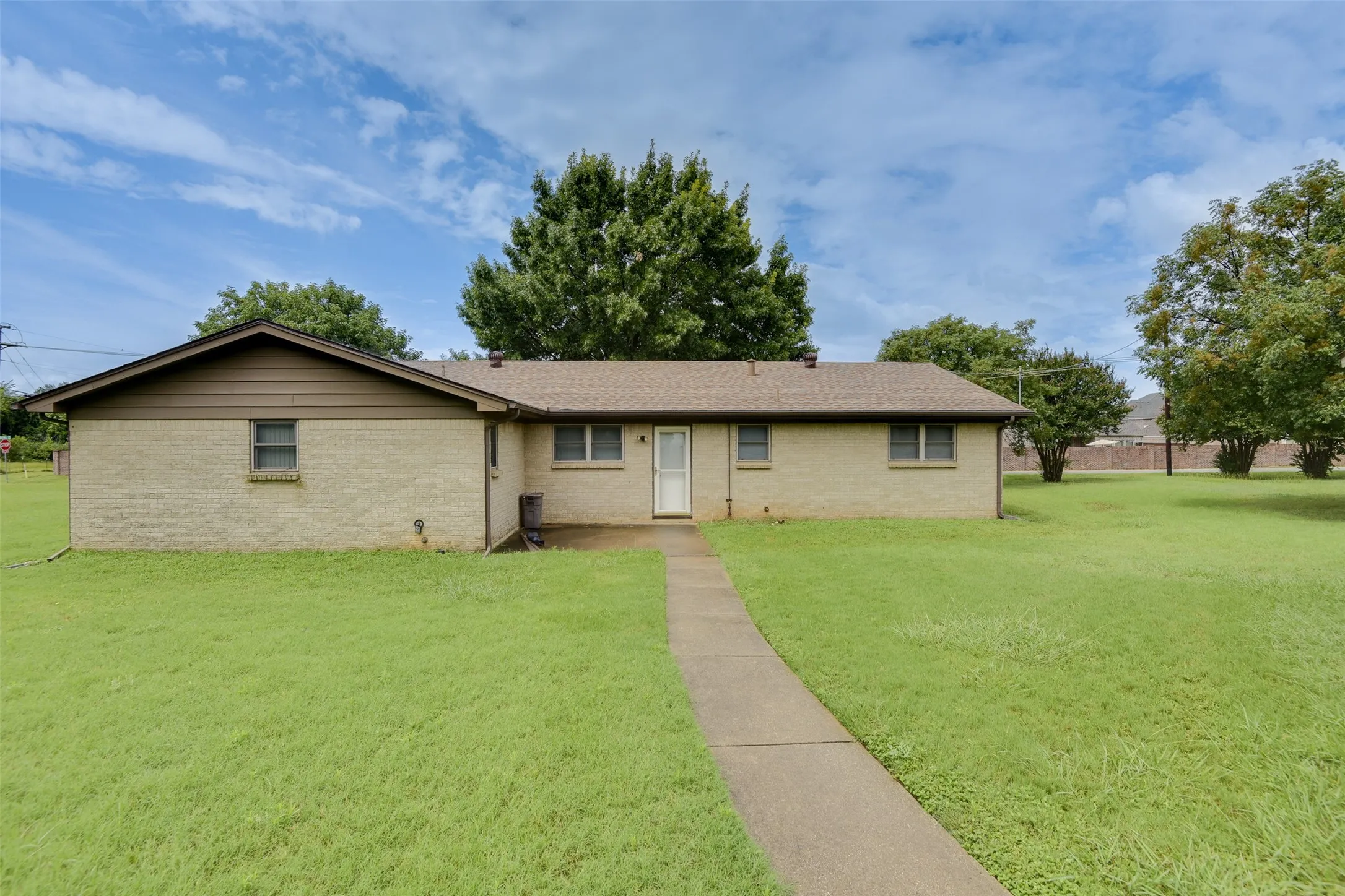Ranch-style home with a front lawn, brick siding, and roof with shingles