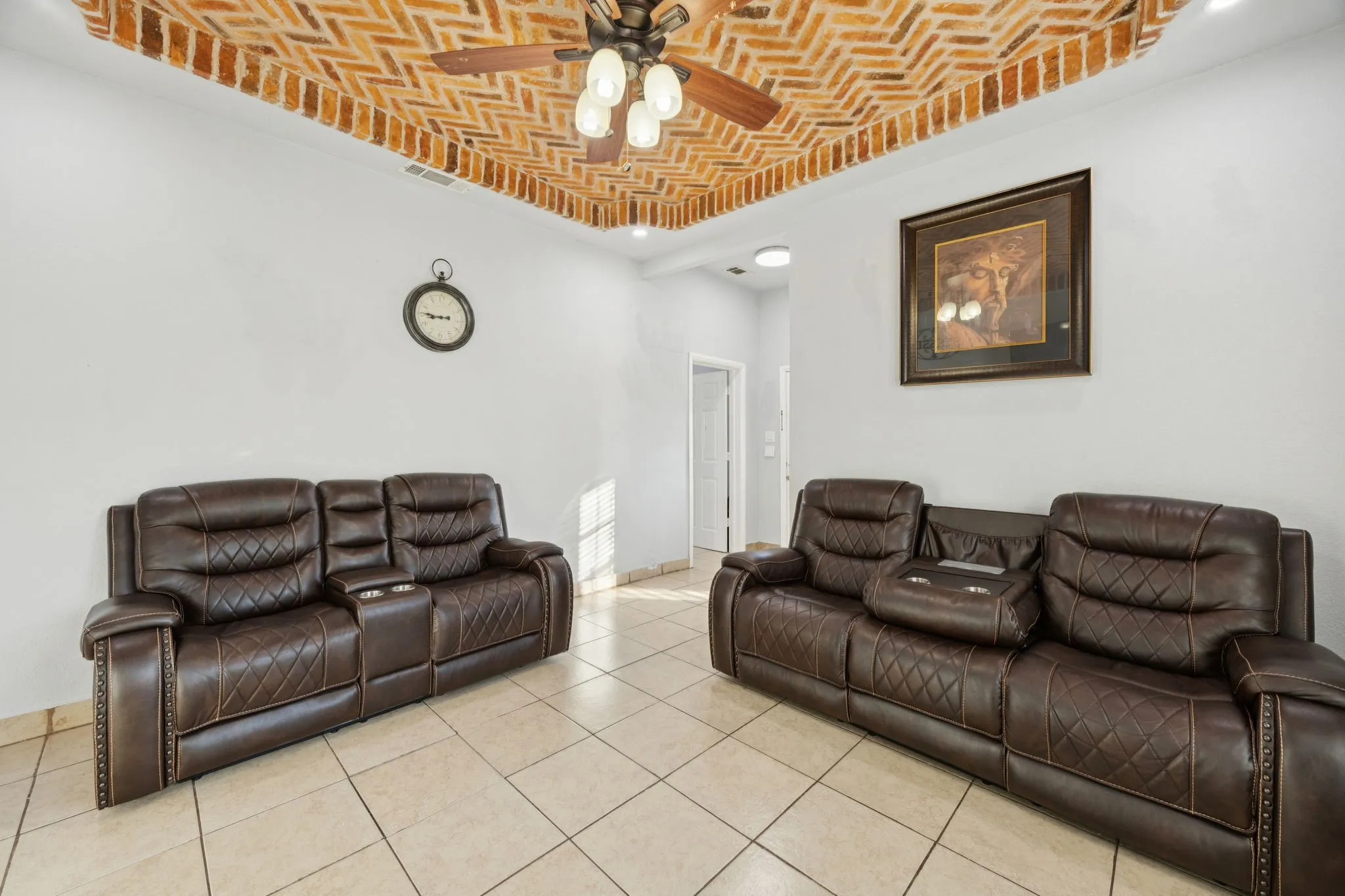 Living room featuring brick ceiling, a ceiling fan, light tile patterned floors, and a tray ceiling