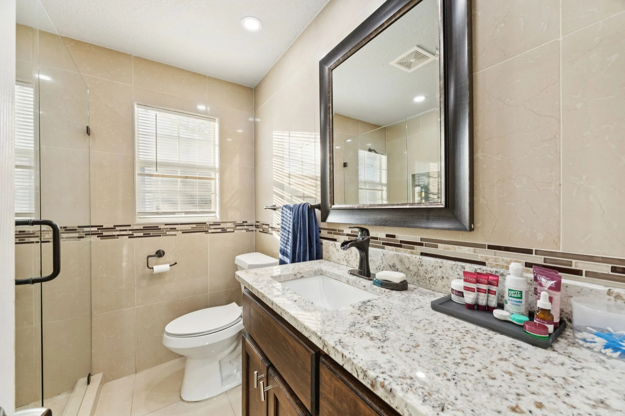 Bathroom featuring a stall shower, vanity, light tile patterned floors, tile walls, and recessed lighting
