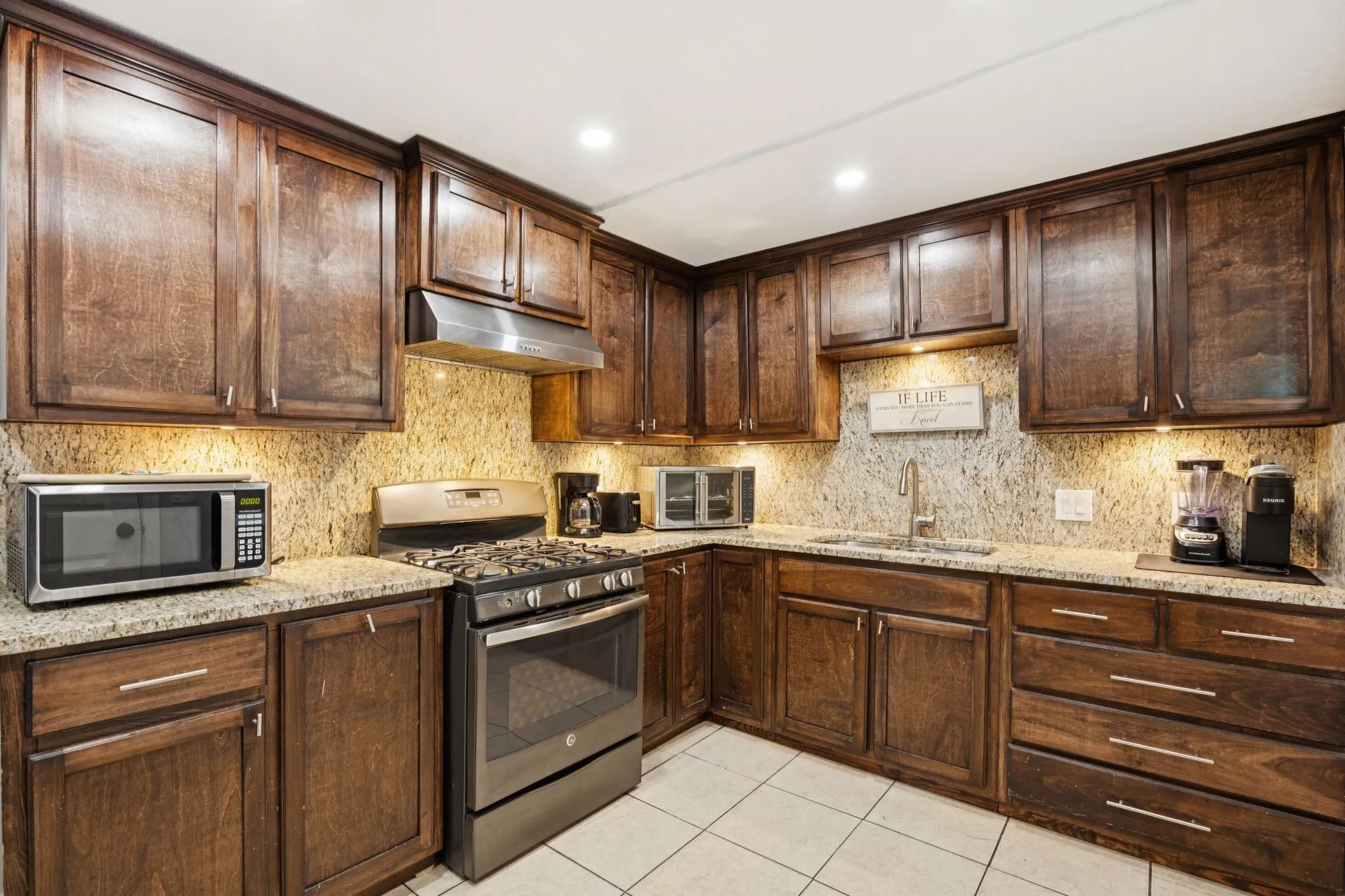 Kitchen featuring appliances with stainless steel finishes, dark brown cabinetry, light stone counters, tasteful backsplash, and recessed lighting