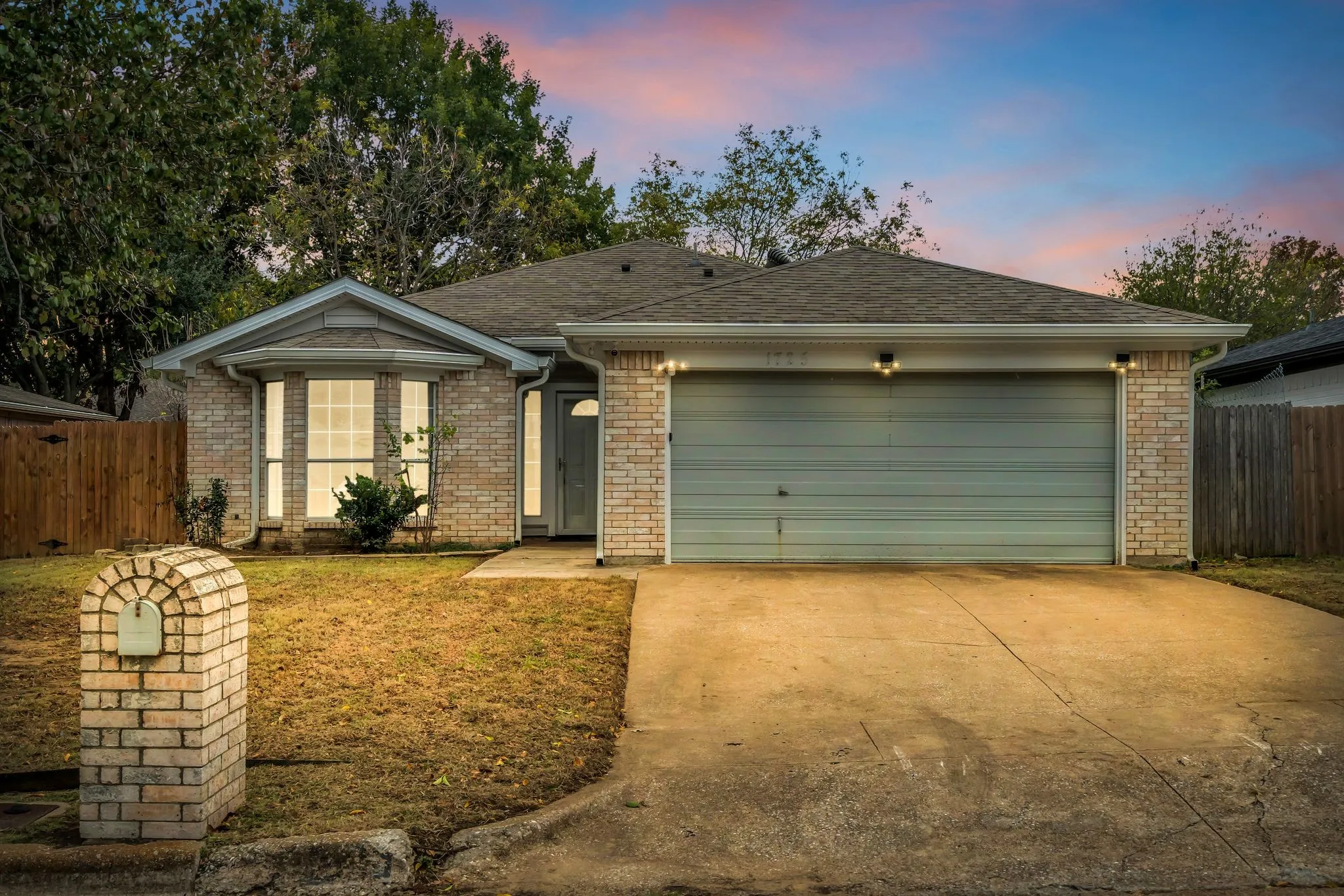 Ranch-style house featuring brick siding, driveway, a shingled roof, and an attached garage