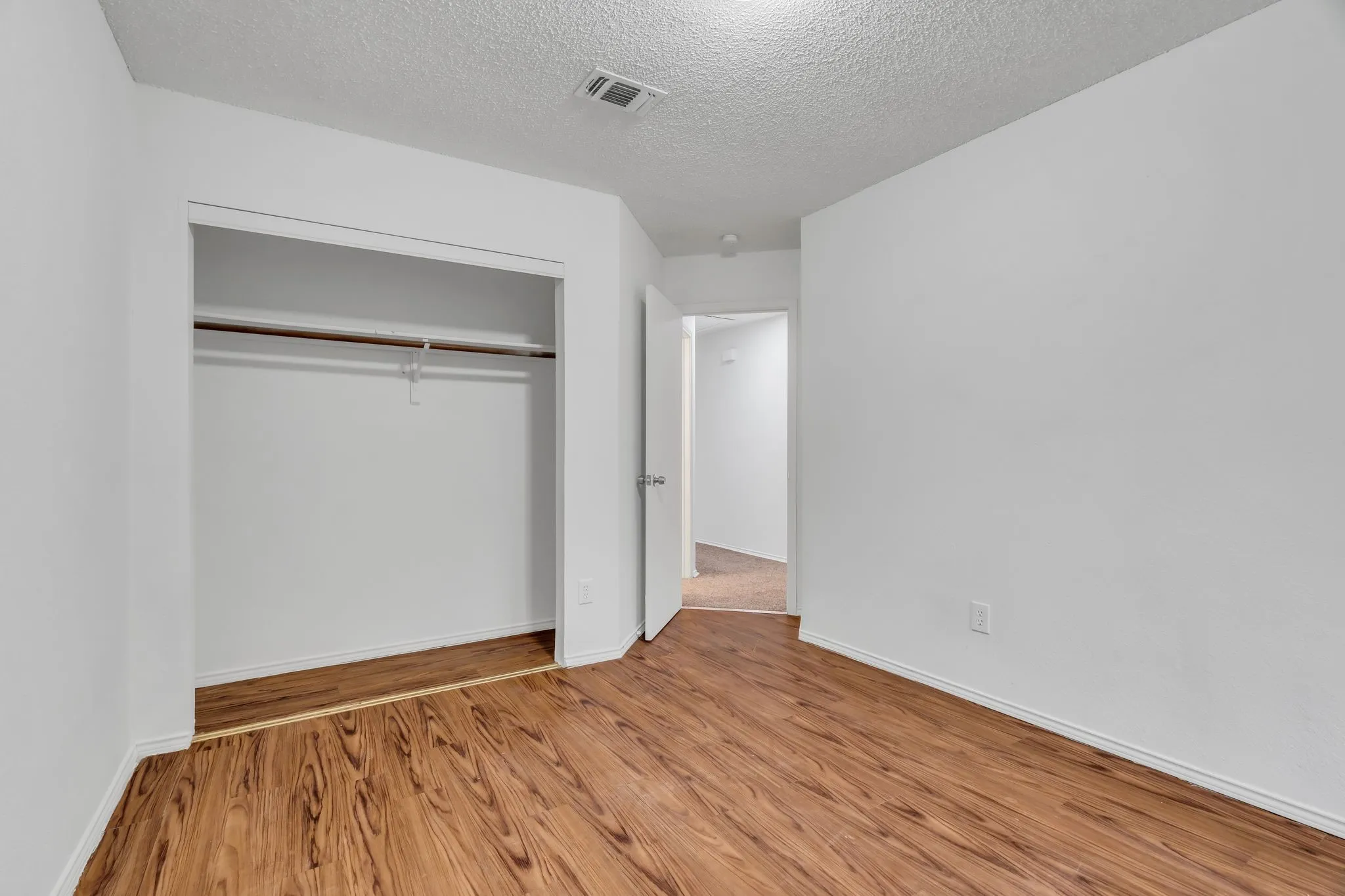 Unfurnished bedroom with wood finished floors, a textured ceiling, and a closet