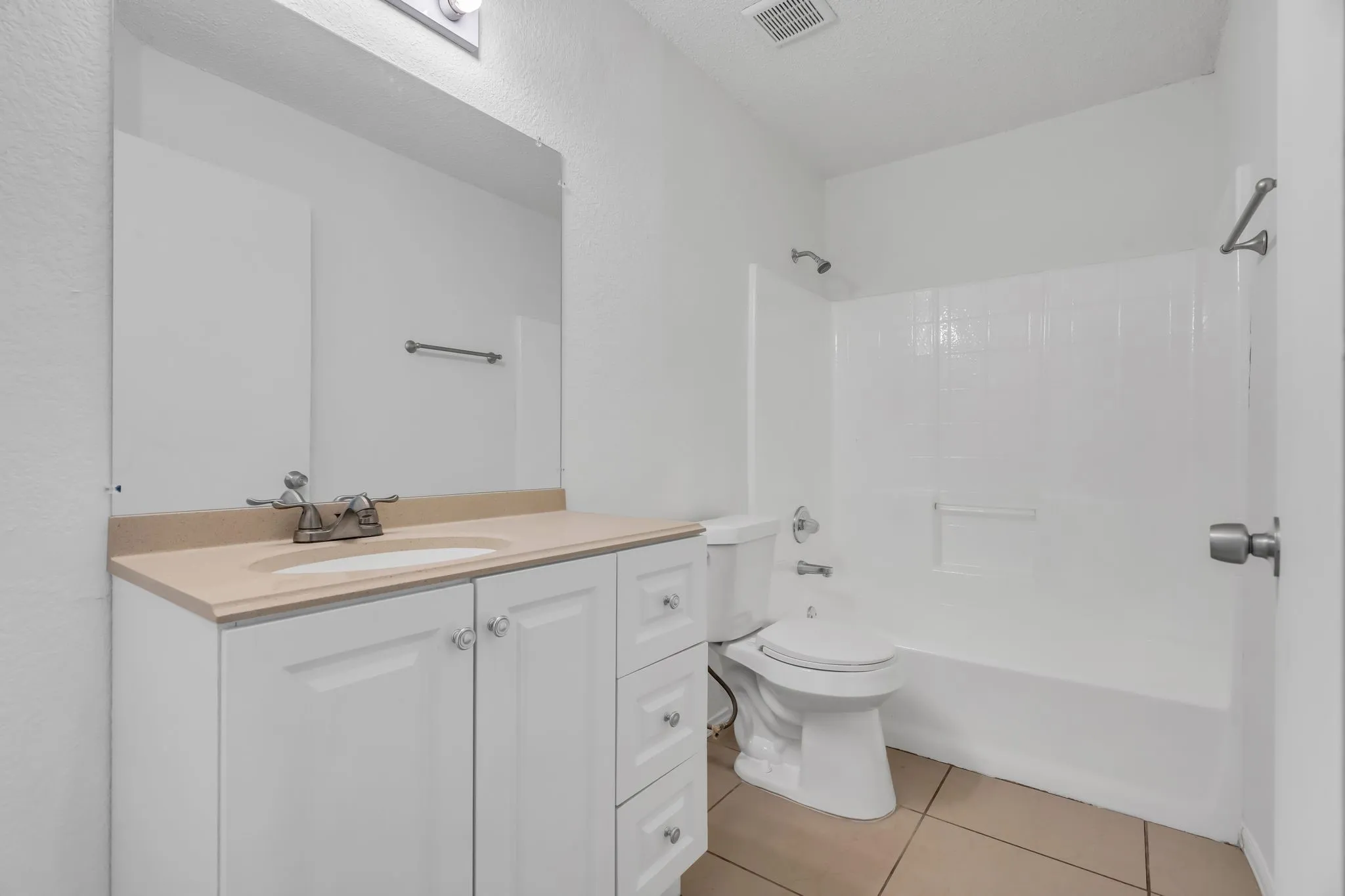 Bathroom with vanity, washtub / shower combination, and light tile patterned floors